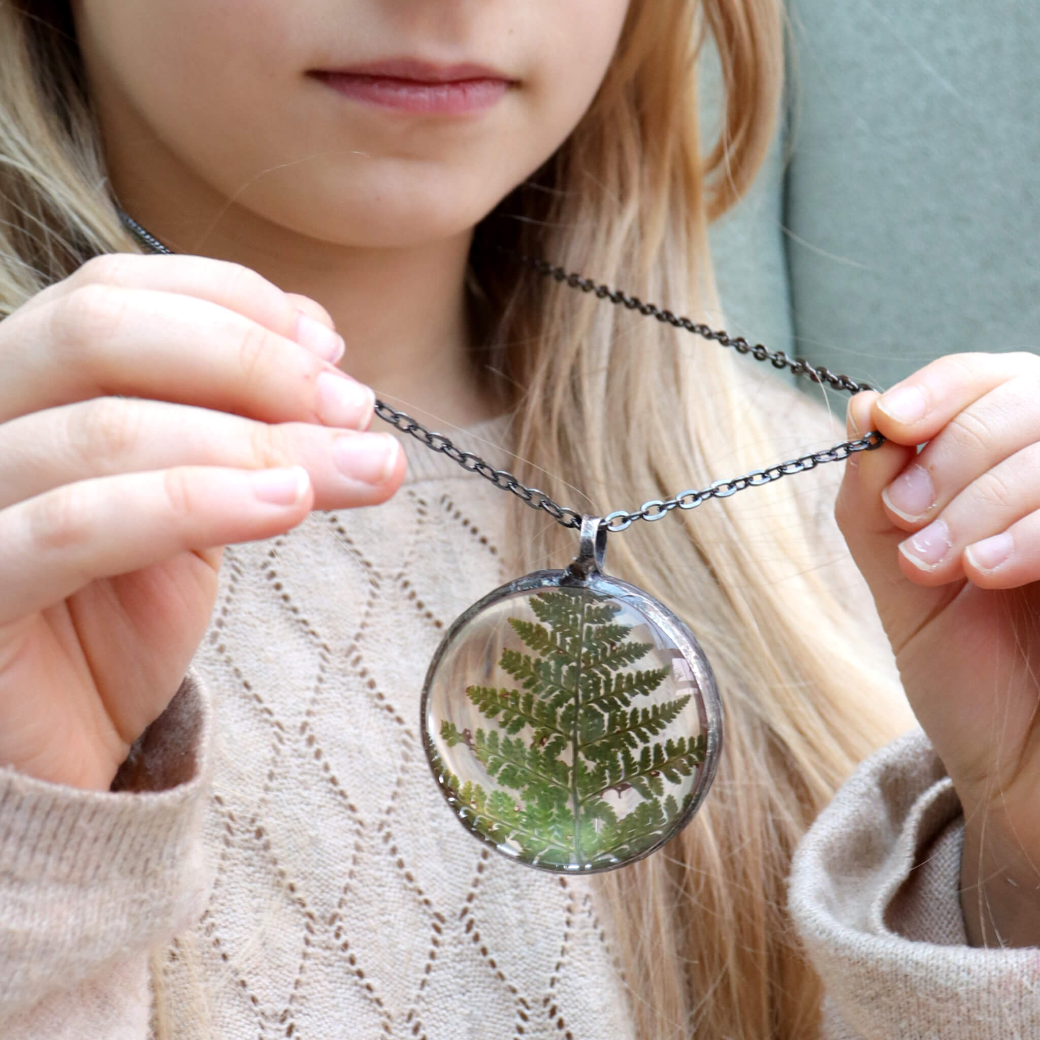 Girl holding her terrarium necklace with dried fern