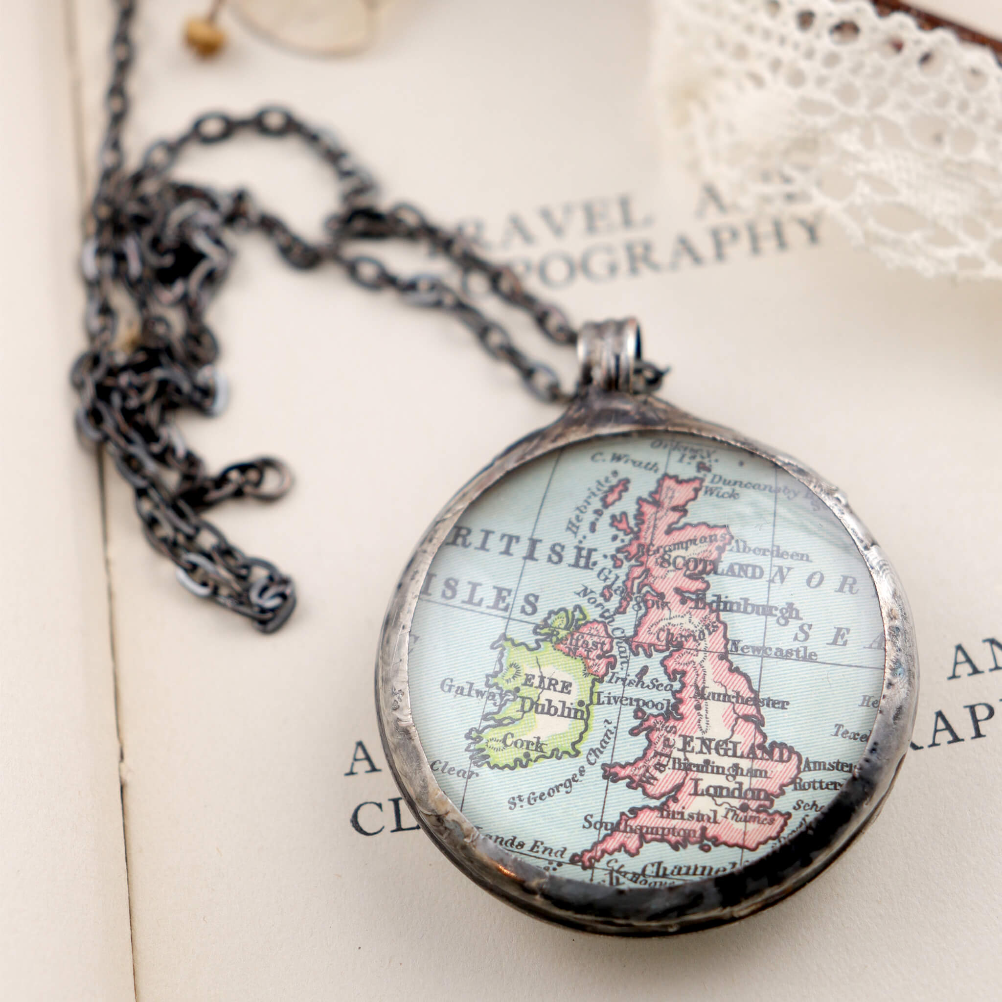 Map of British Isles framed into Tiffany style statement necklace lying on a book