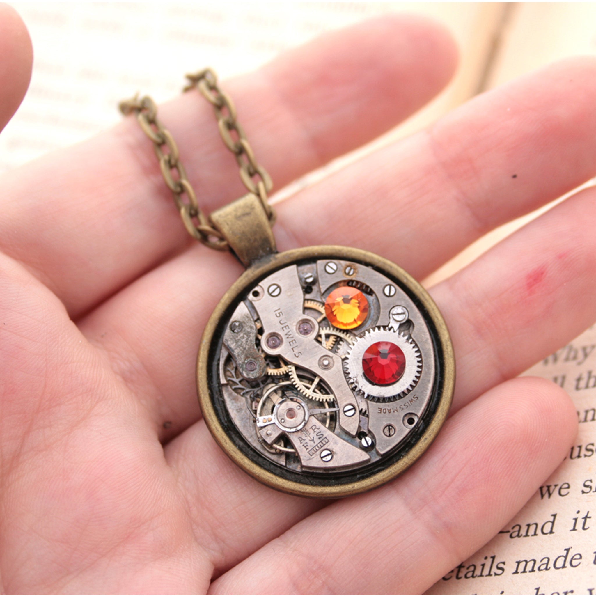 Dark academia necklace made of watch mechanism and Swarovski crystals lying on hand