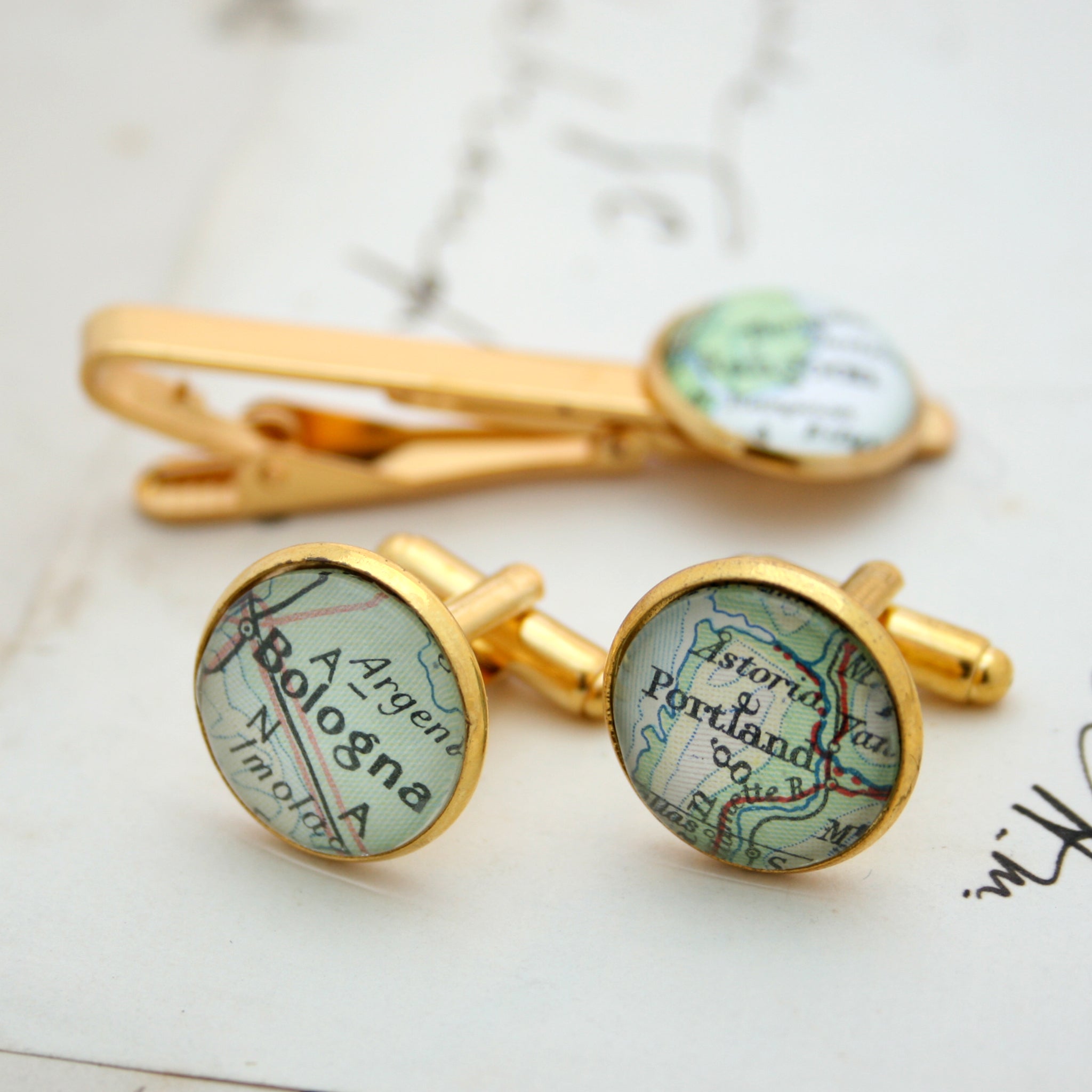 Tie clip and cufflinks in gold color featuring selection of map locations