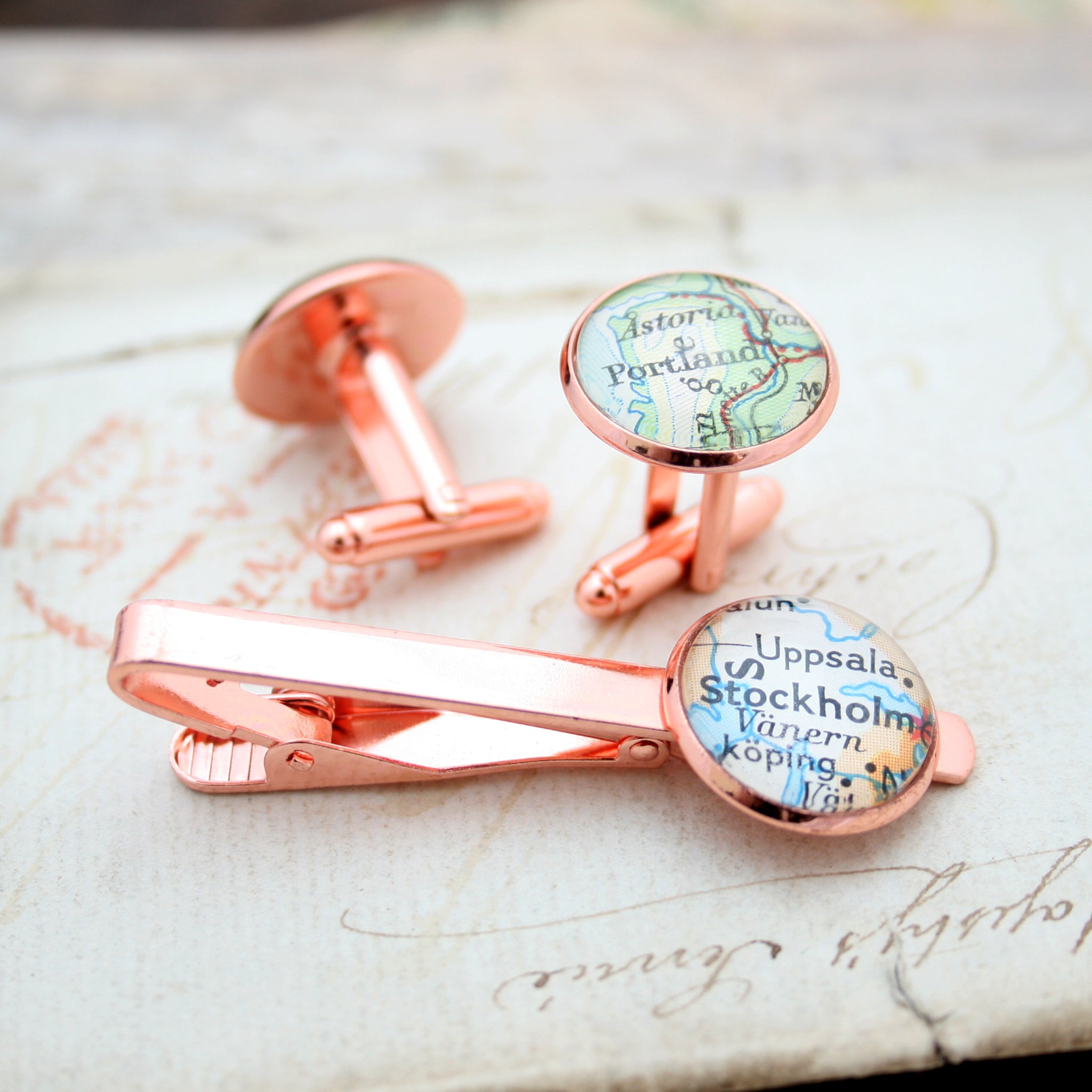Tie clip and cufflinks in rose gold color featuring selection of map locations