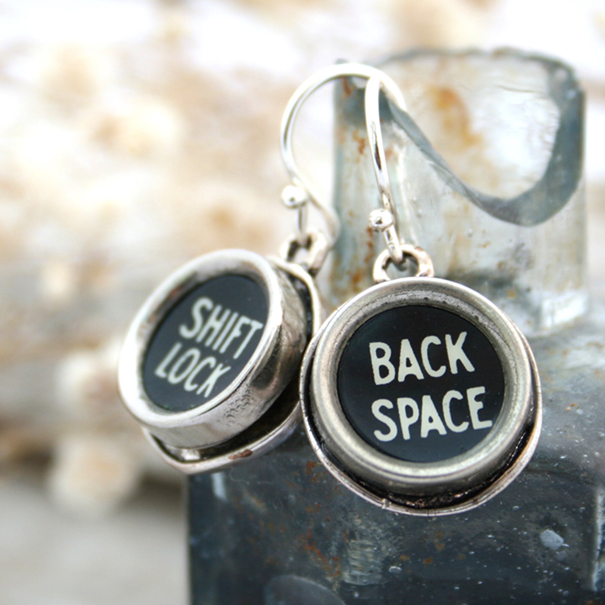 Typewriter keys Shift Lock and Back space earrings hanging from an inkwell