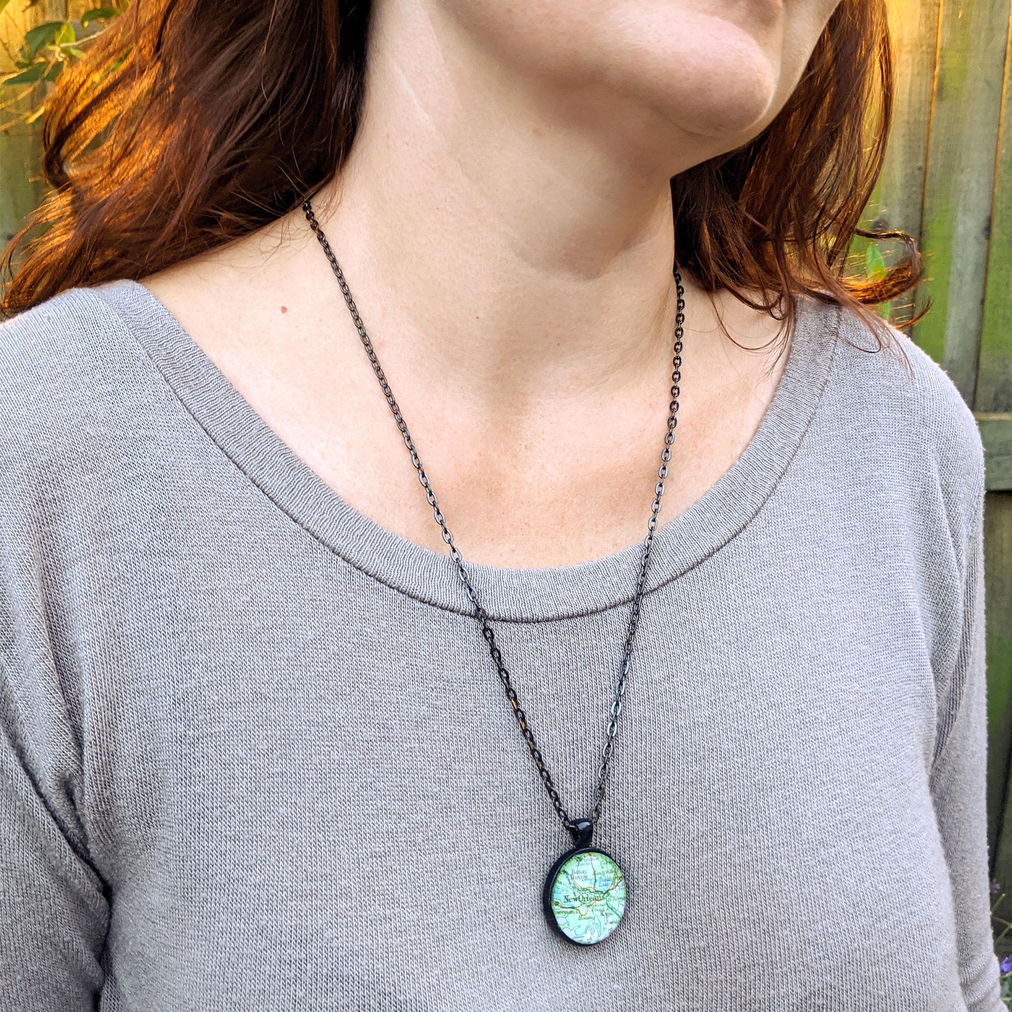 Two sided map necklace in black color worn by a woman