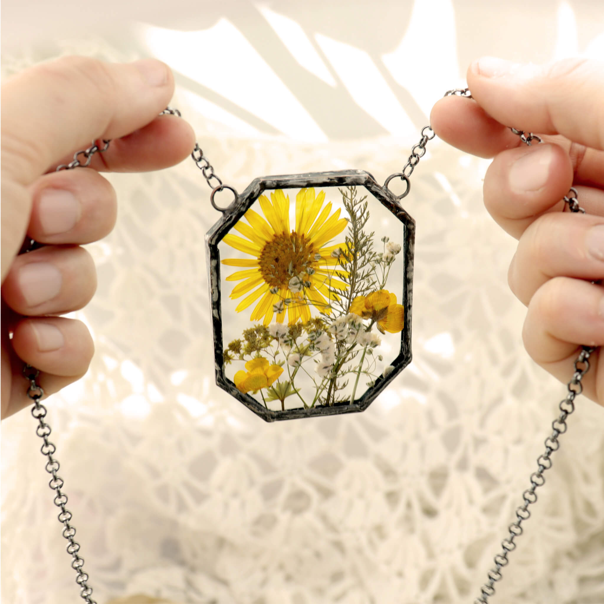on a white background hands holding chain of a yellow flowers glass necklace