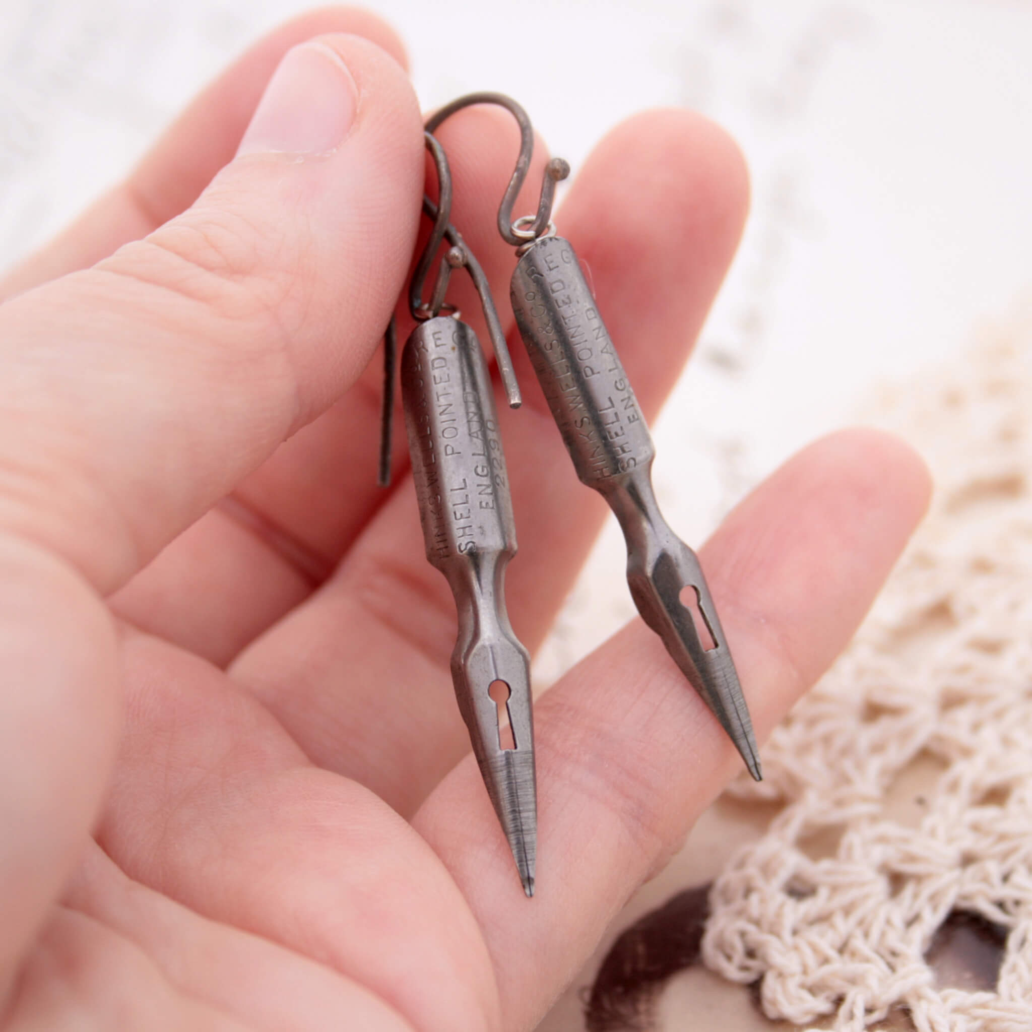 quirky earrings made of antique pen nibs hold in hand