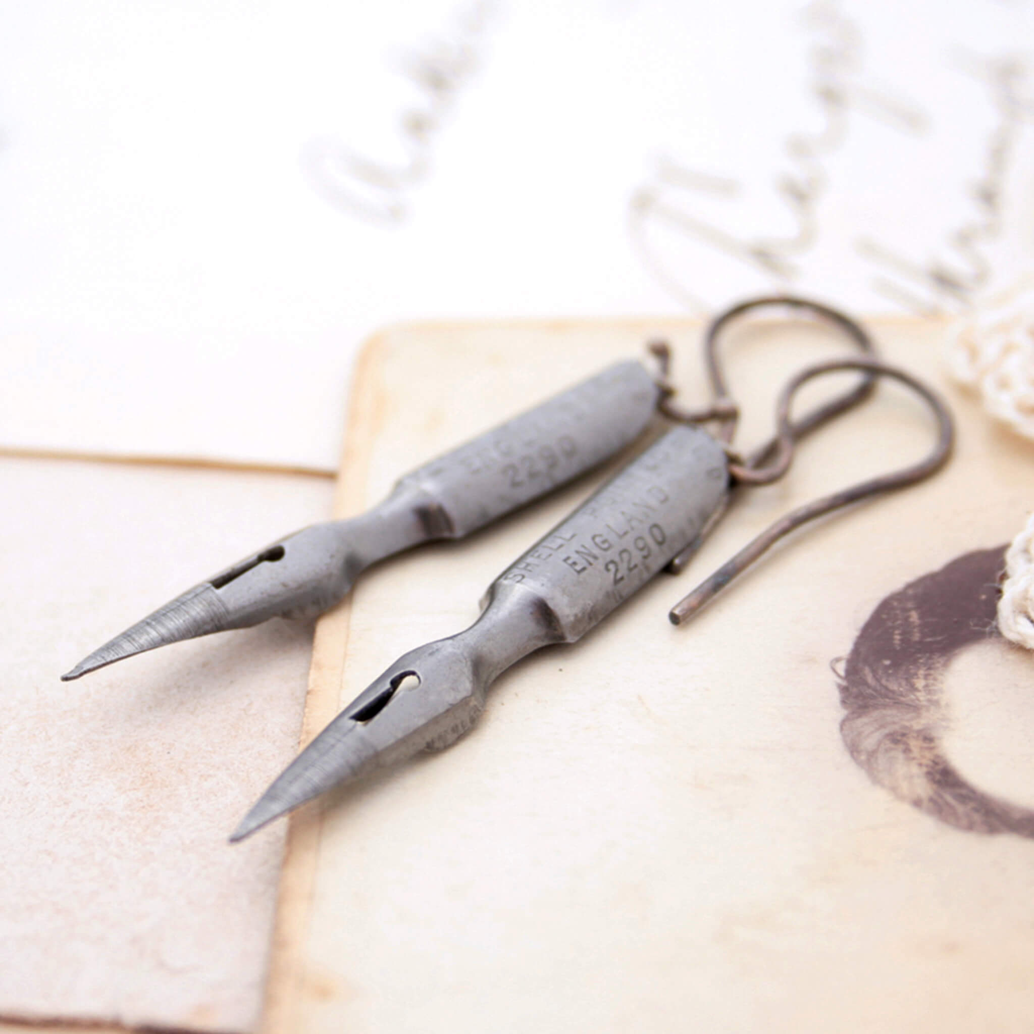 quirky earrings made of antique pen nibs lying on an old photo