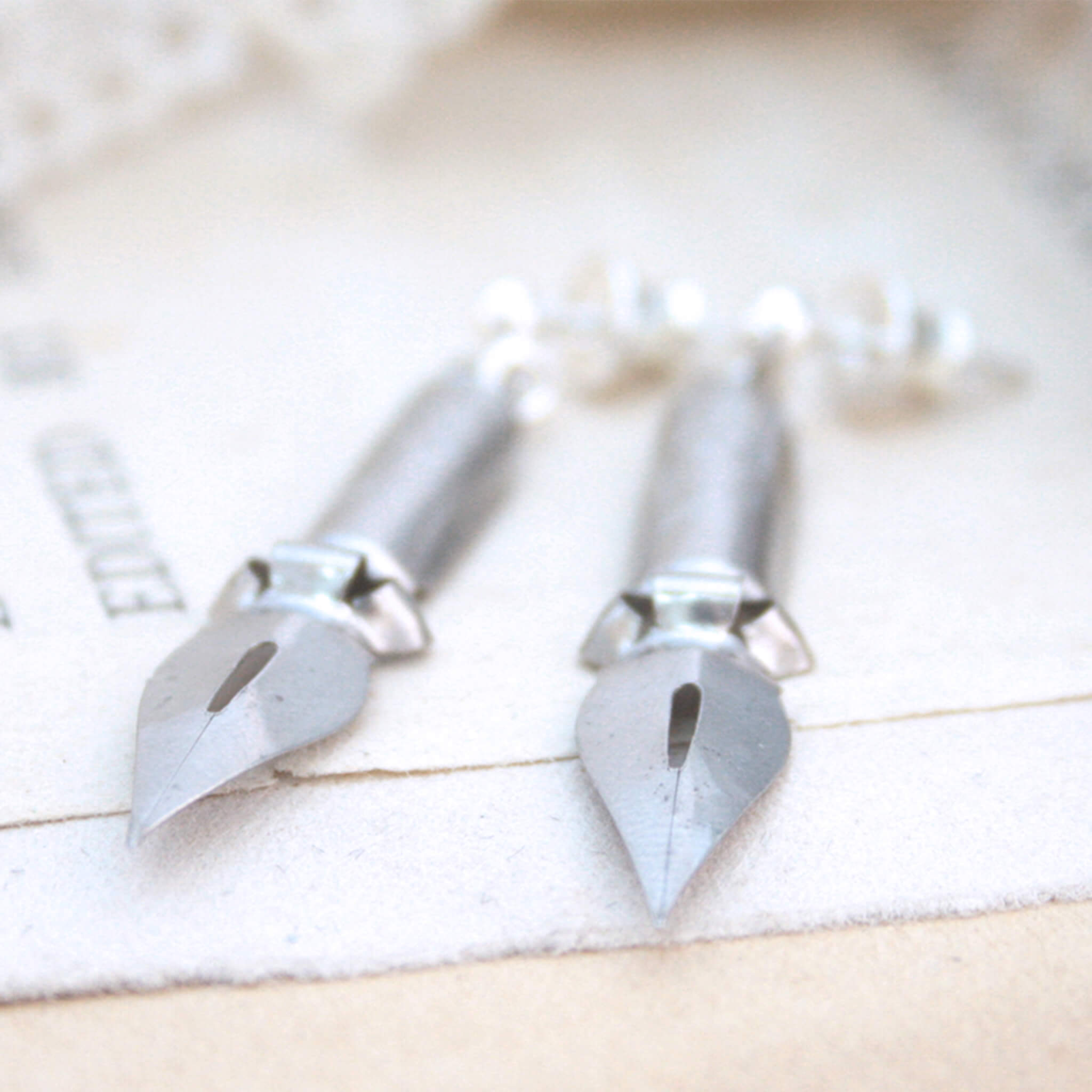 quirky earrings made of antique pen nibs lying on an old book