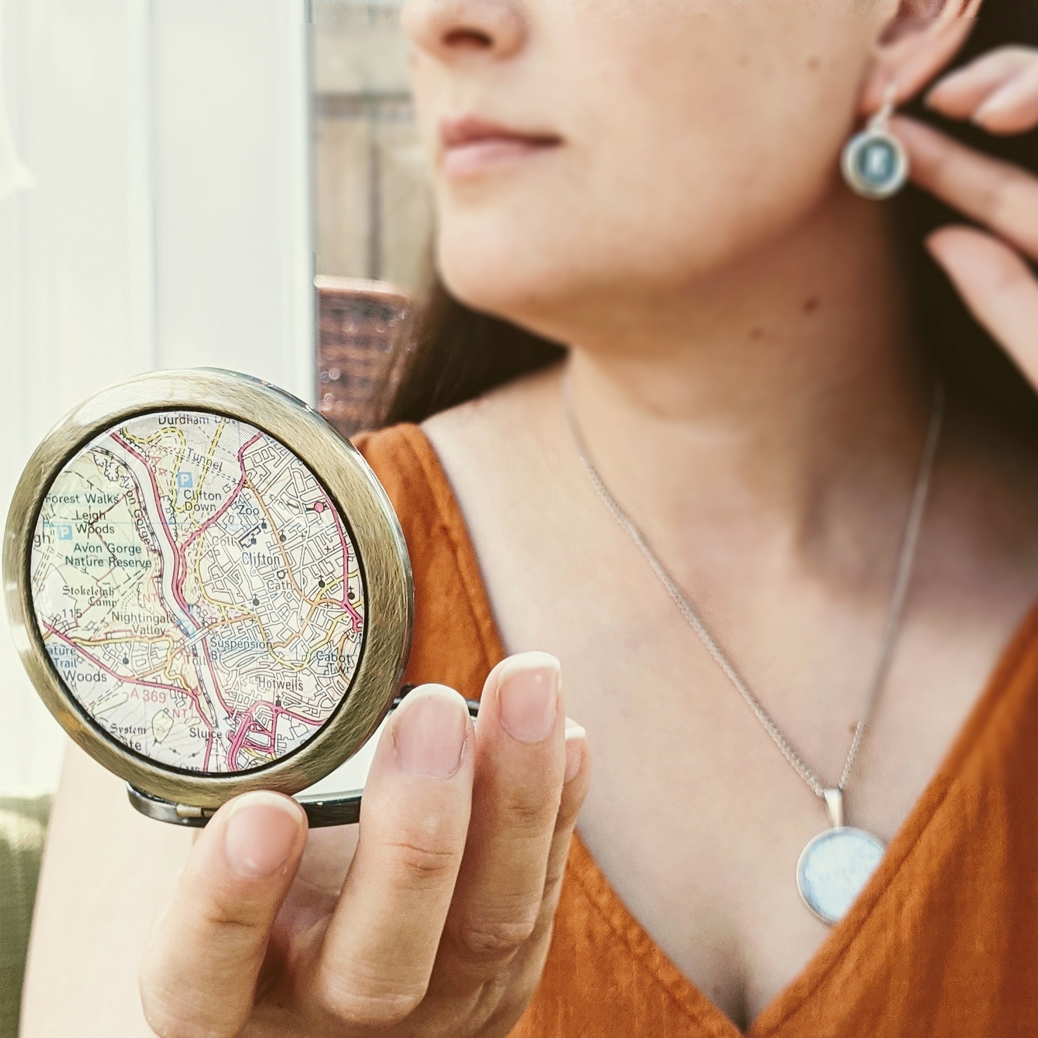 woman checking her makeup in custom map compact mirror