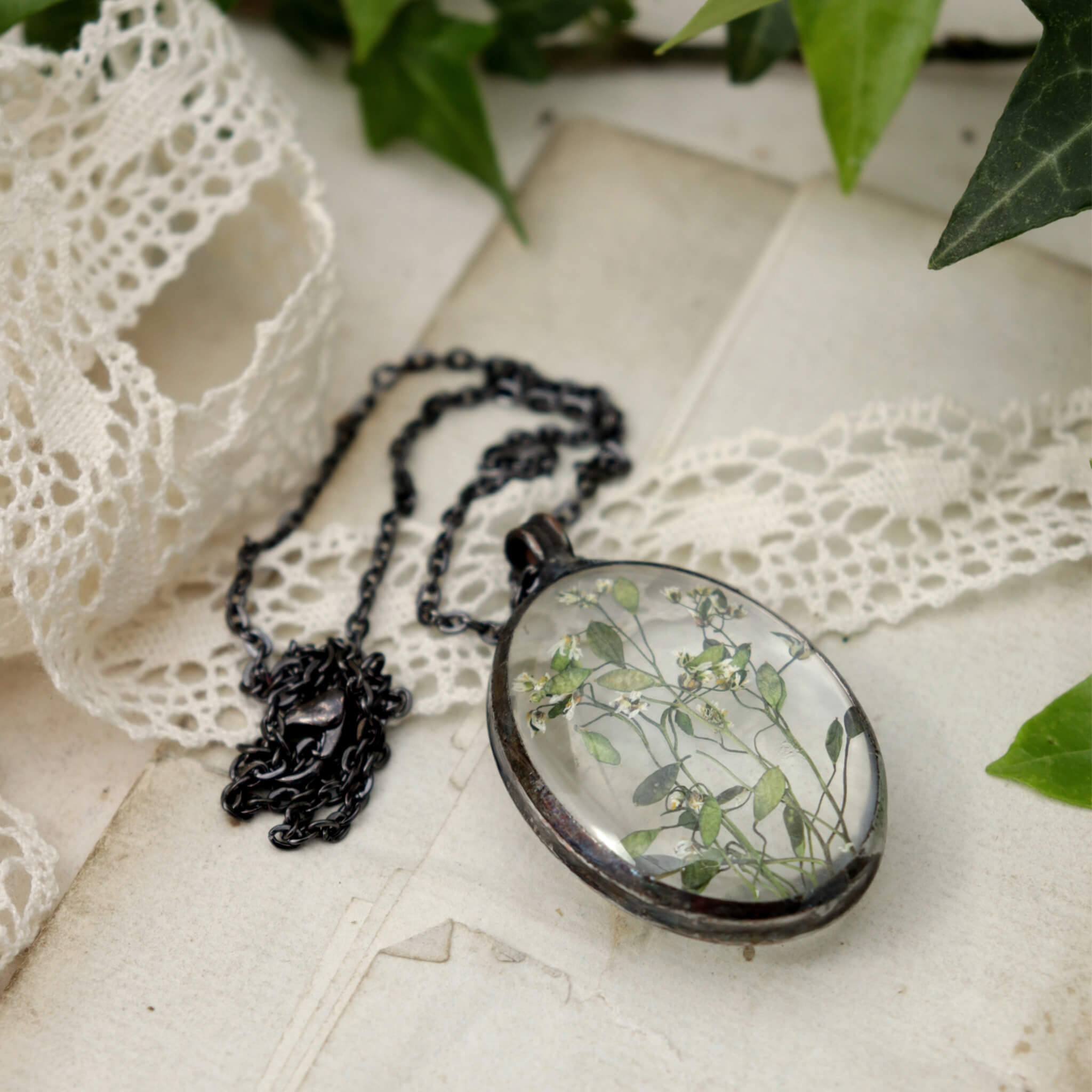  Big glass necklace with some flowers inside it on an old paper and lace