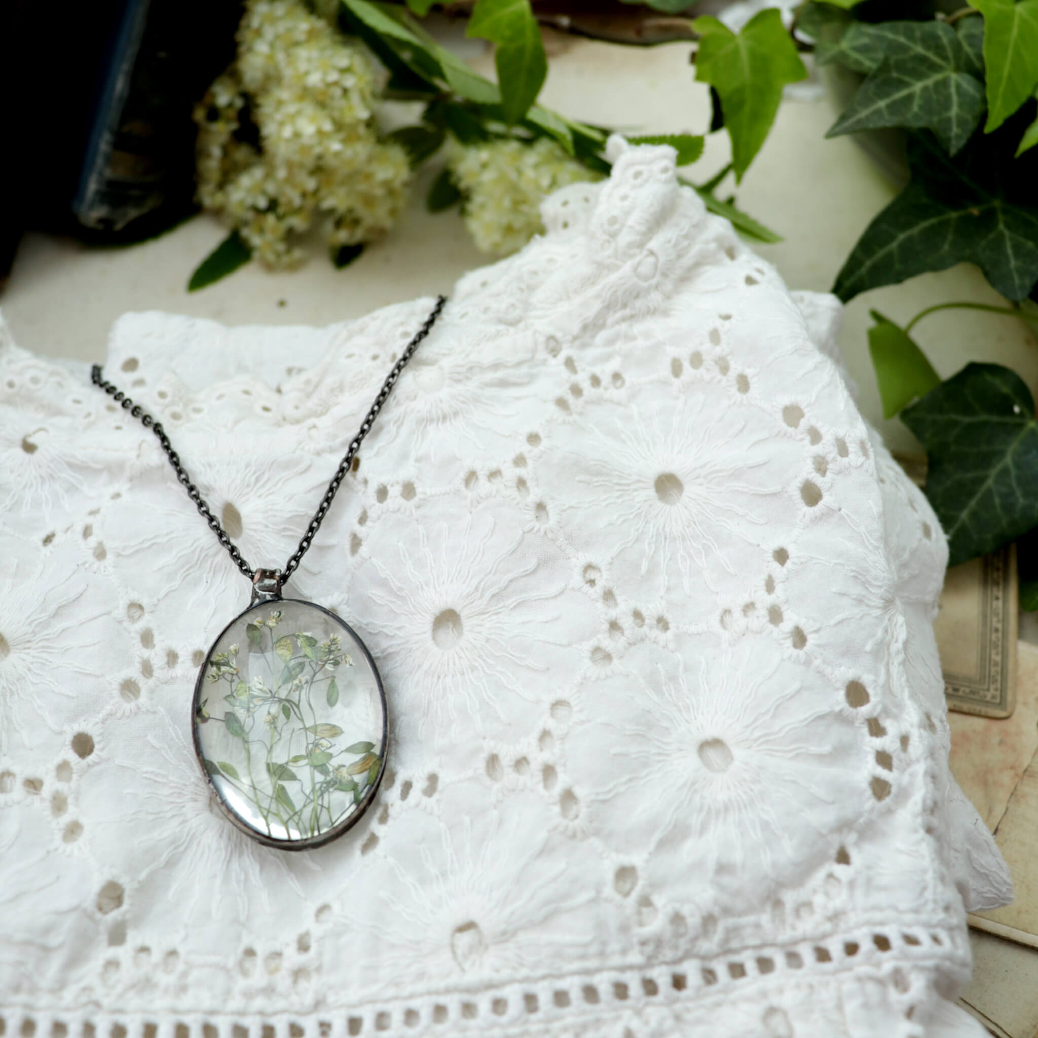  Big glass necklace with some flowers inside it lying on a white blouse