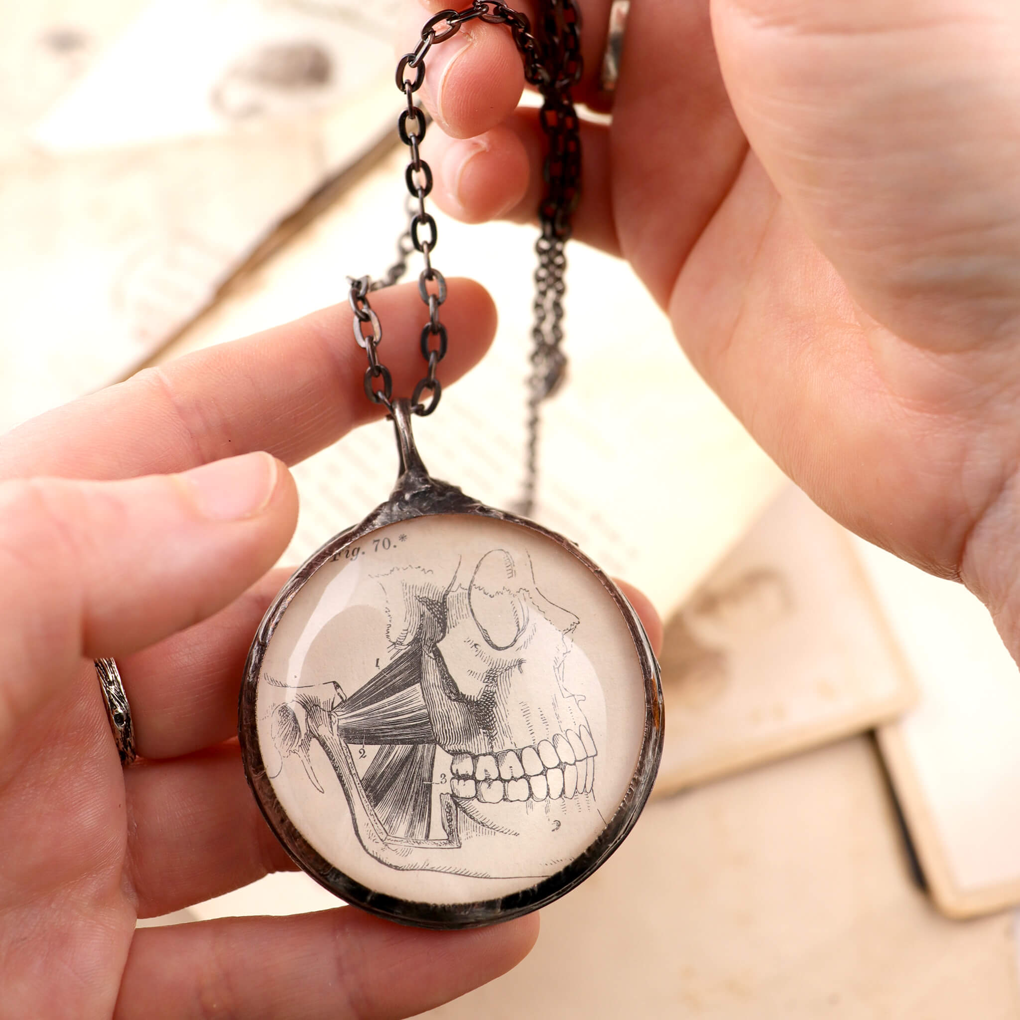 hands holding skull illustration stained glass necklace