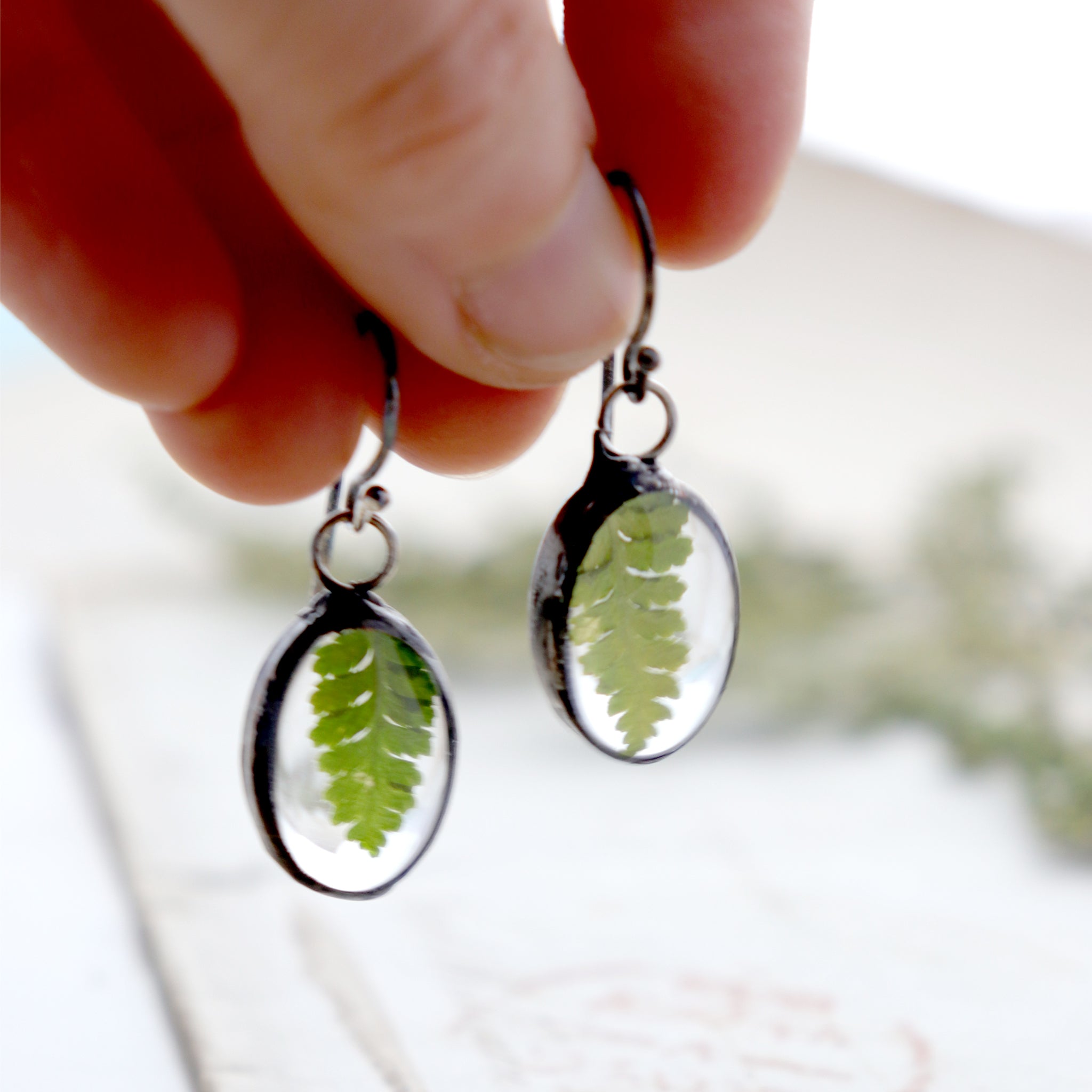 Earrings with real fern being hold in hand