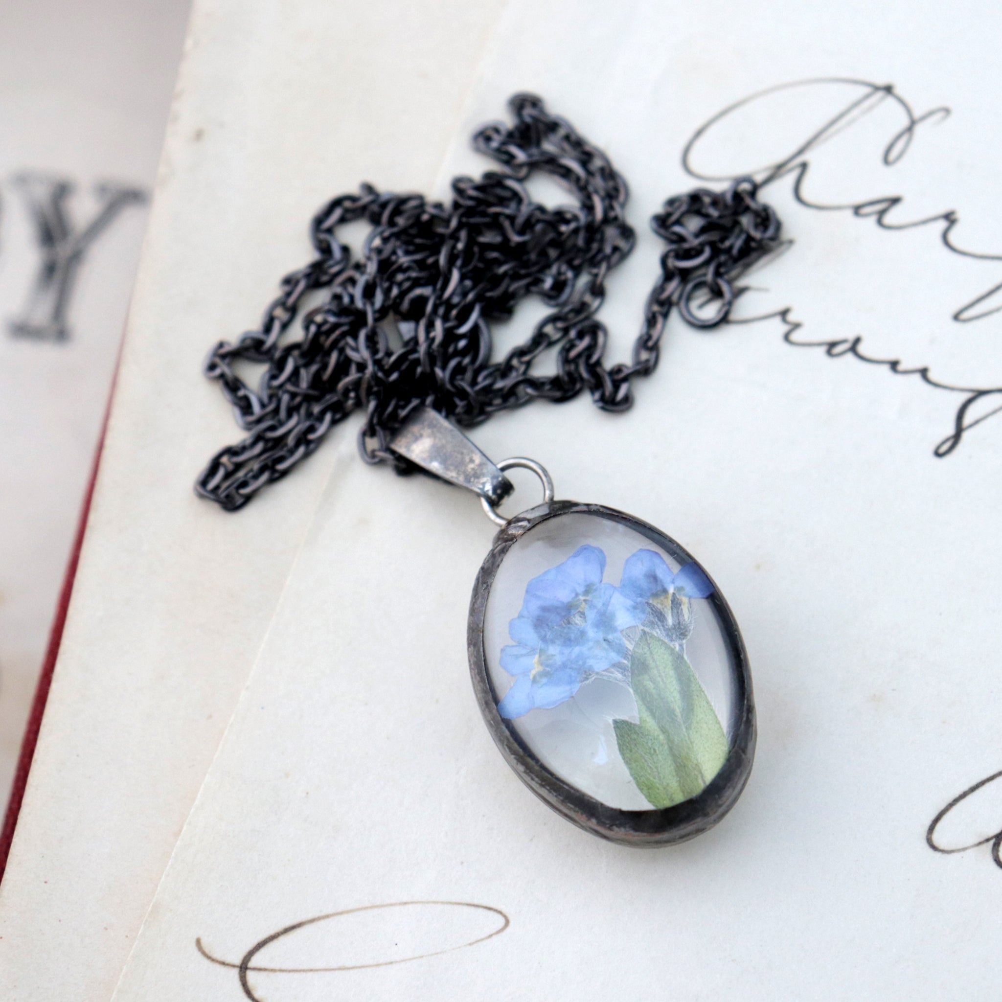 Forget-me-not oval little necklace lying on an old book