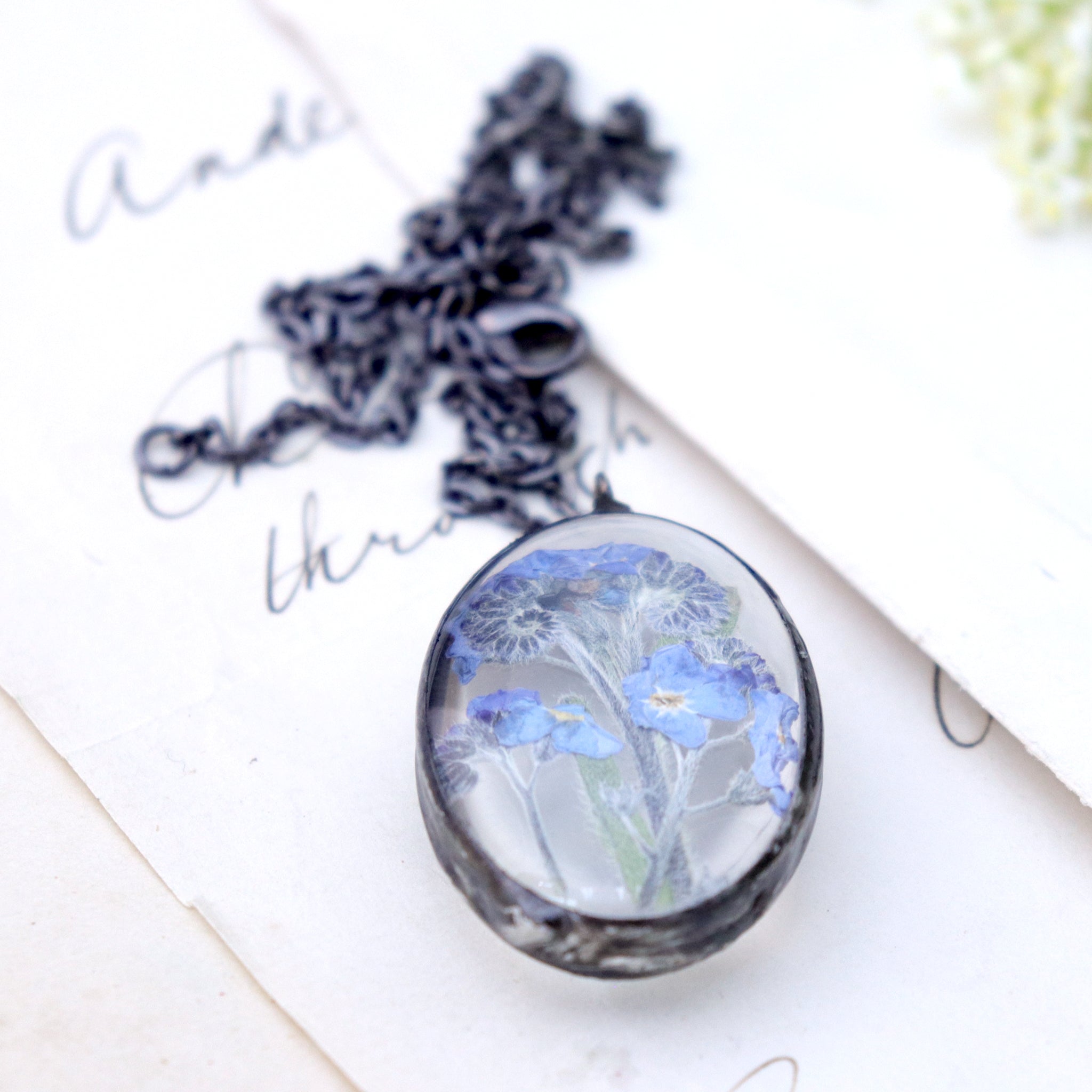 oval Forget-me-not necklaces lying on an old book
