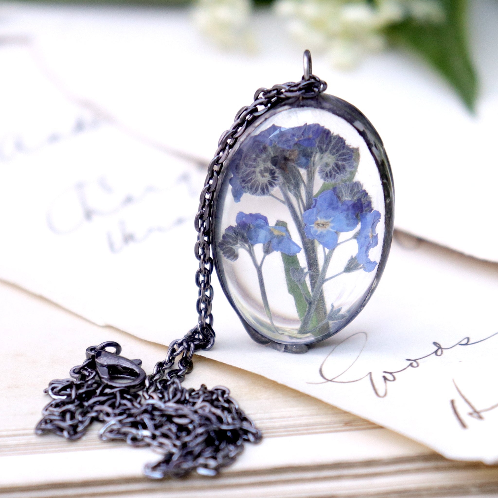 Forget-me-not oval necklace standing on the edge on an old book