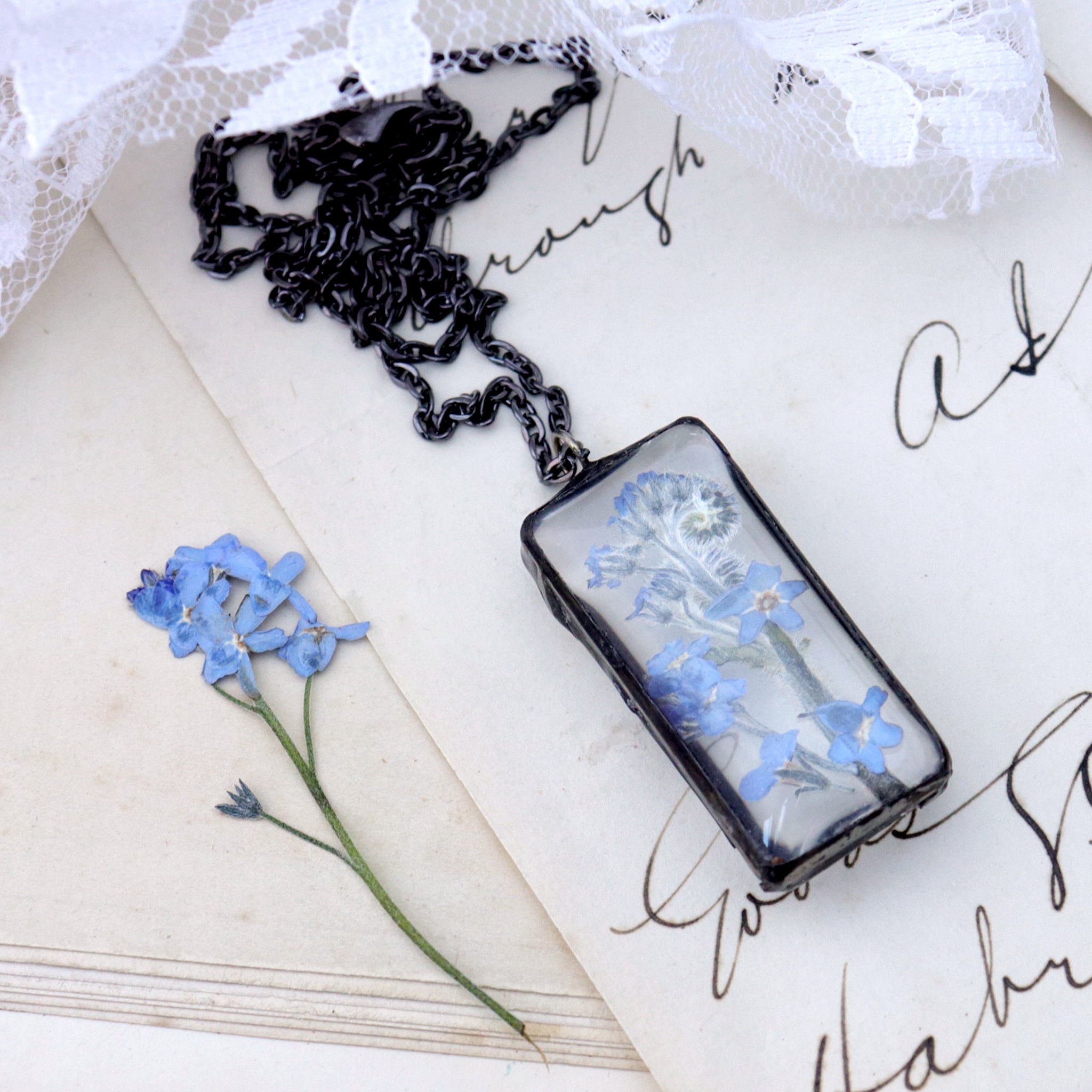 rectangular Forget-me-not necklaces lying on an old book
