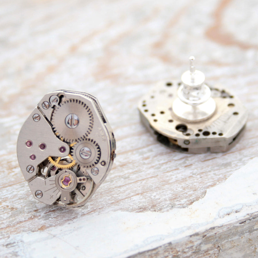 watch movements turned into stud earrings lying on a white painted wood