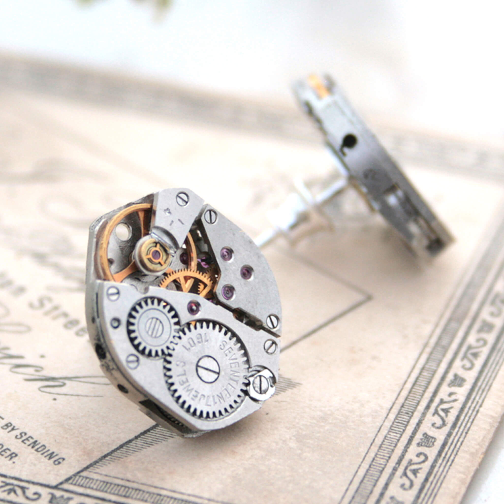 watch movements turned into stud earrings lying on old papers