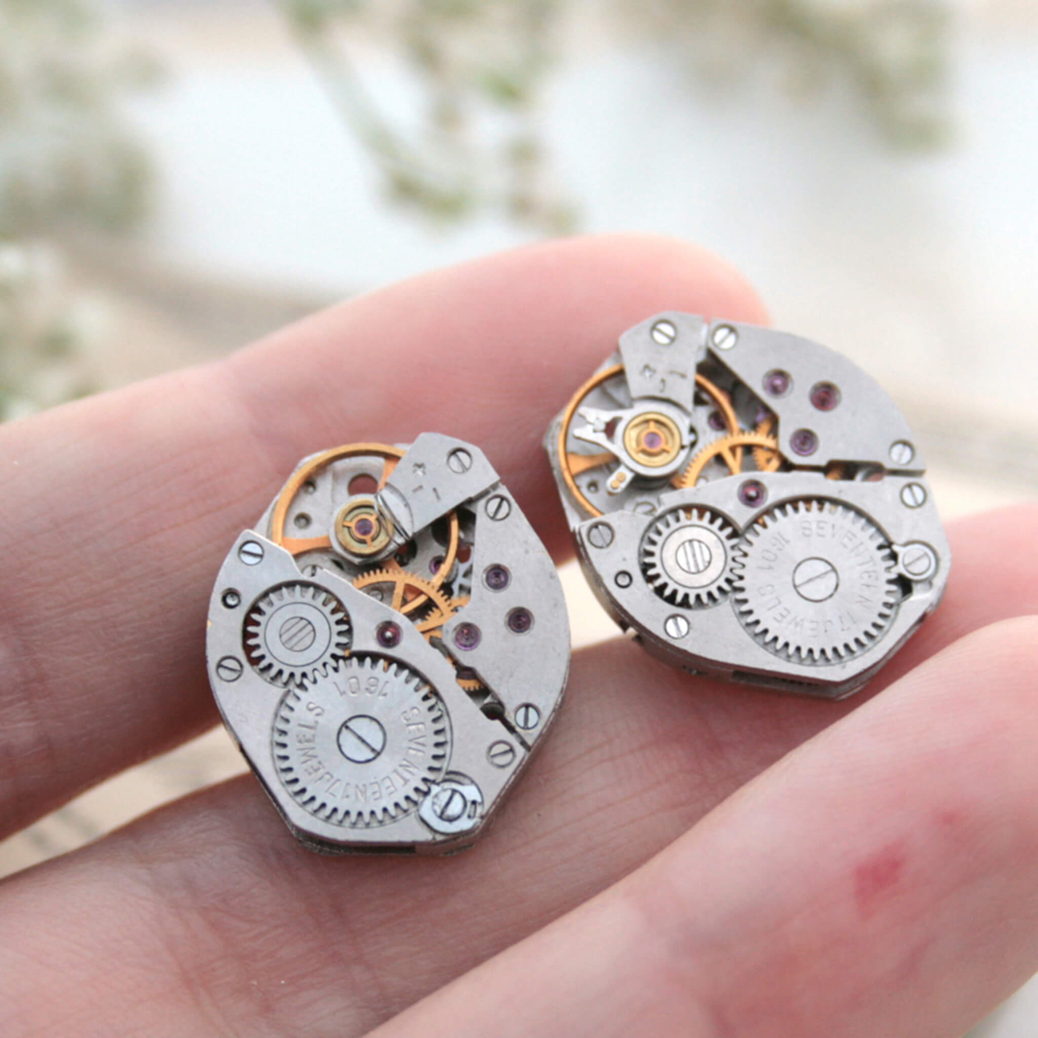 watch movements turned into stud earrings lying on a hand