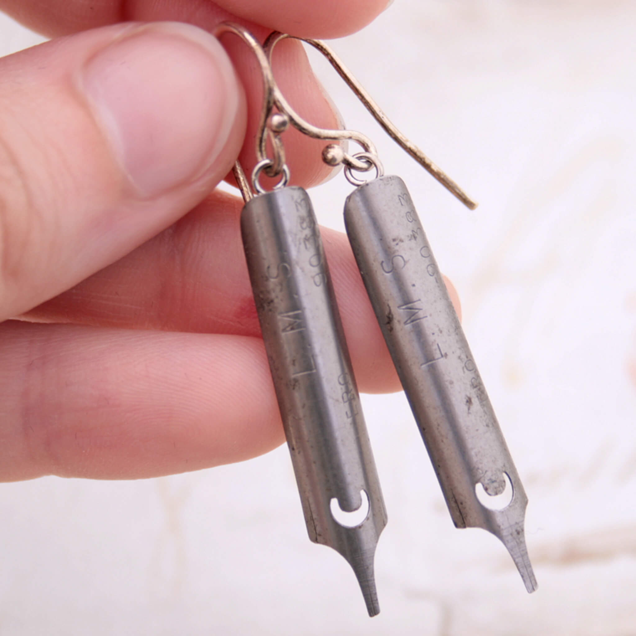 steel pen nib earrings being hold in hand