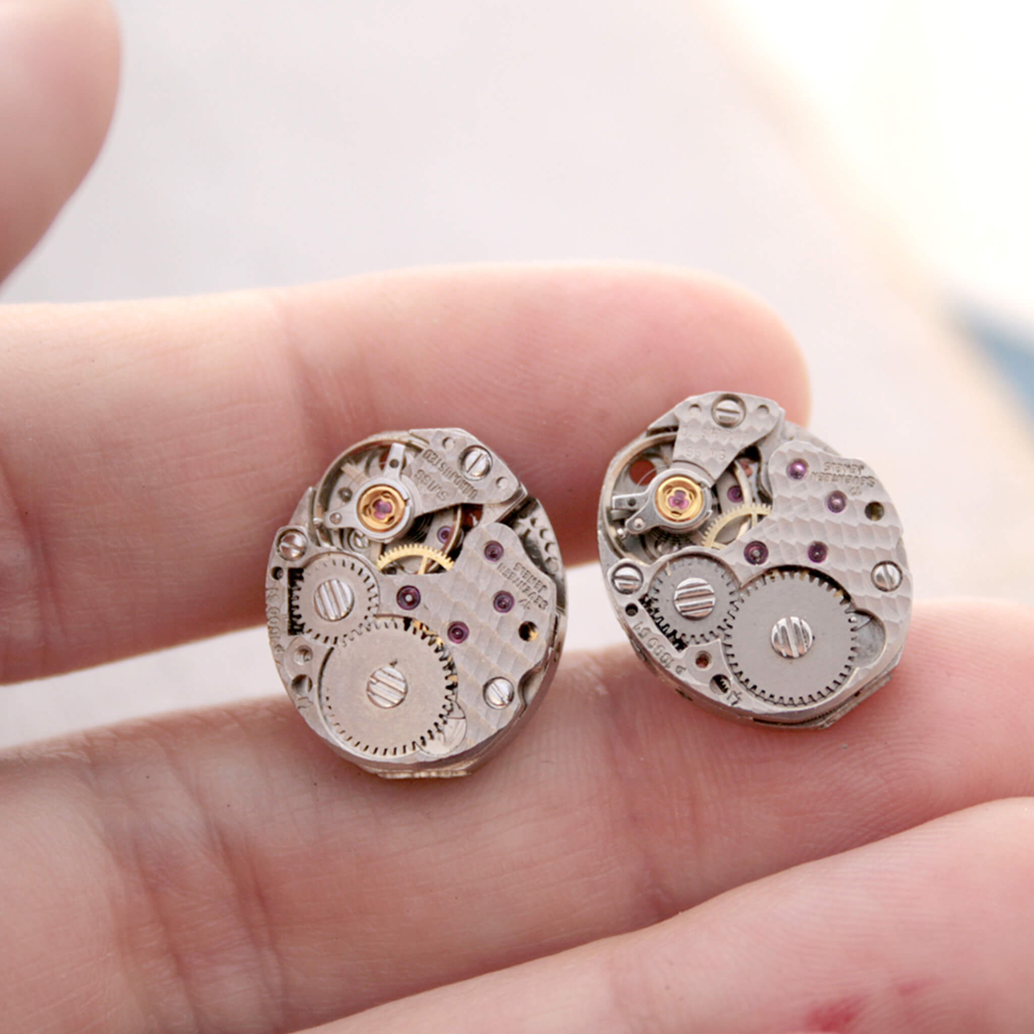 Oval Watch movements turned into stud earrings being hold in hand