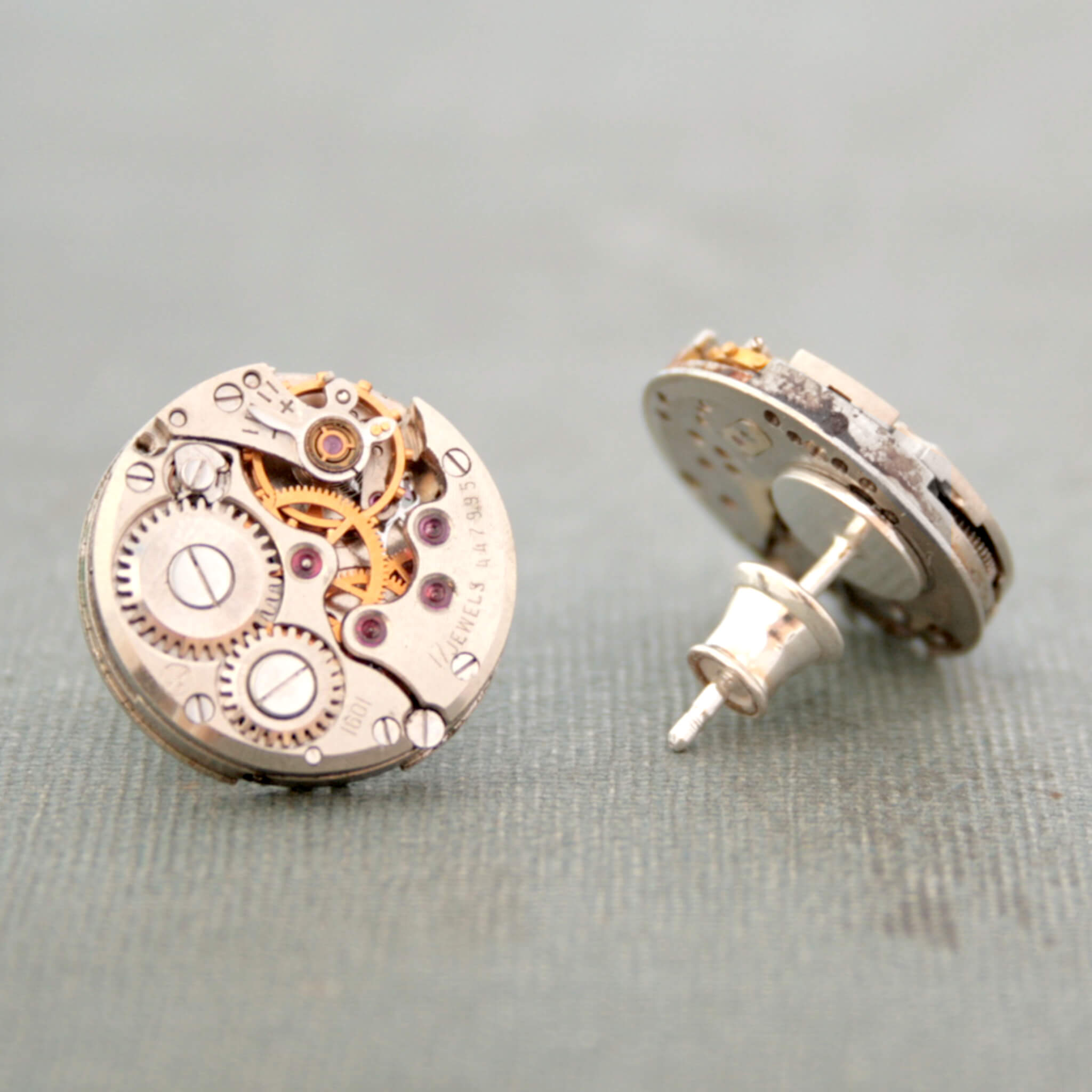 Round Watch movements turned into stud earrings lying on a vintage book