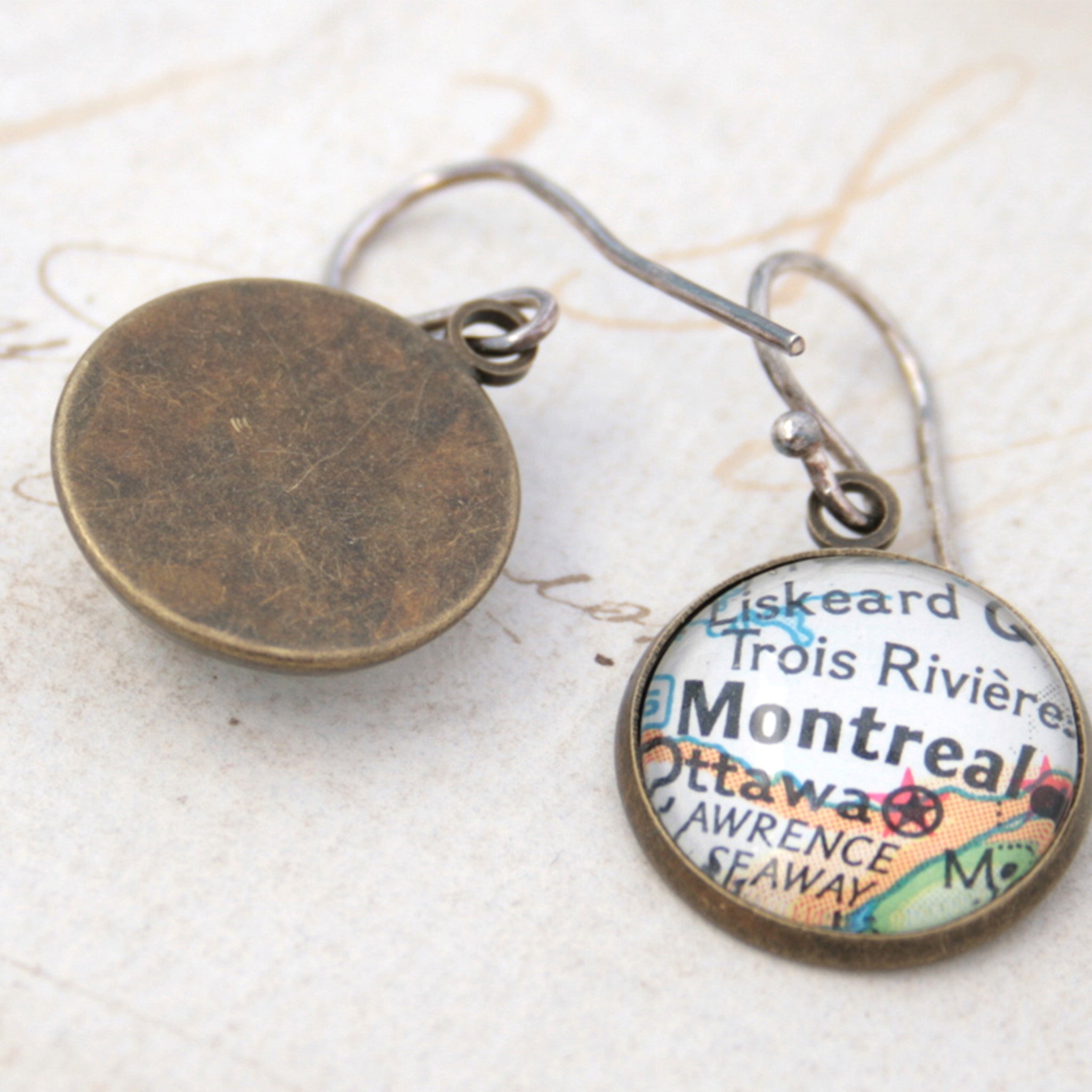 Bronze dangle earrings featuring maps of Stockholm and Montreal