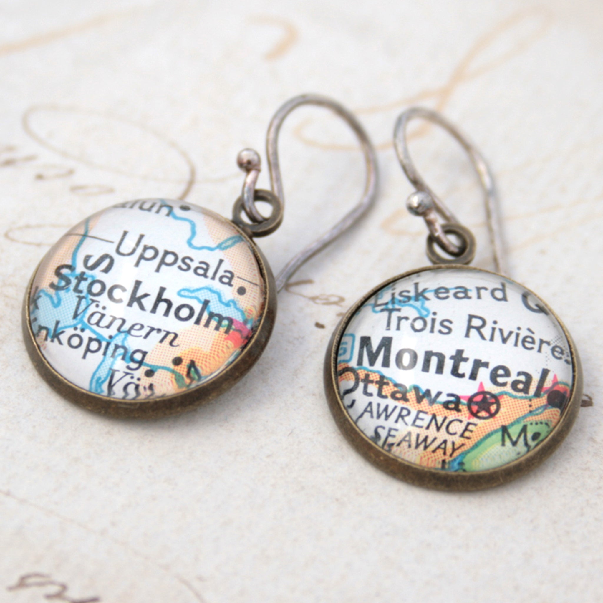 Bronze dangle earrings featuring maps of Stockholm and Montreal