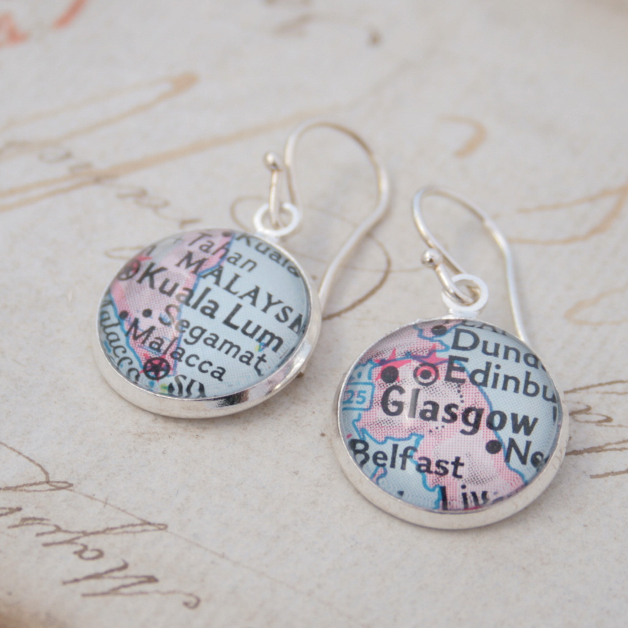 silver dangle earrings featuring maps of Glasgow and Kuala Lumpur