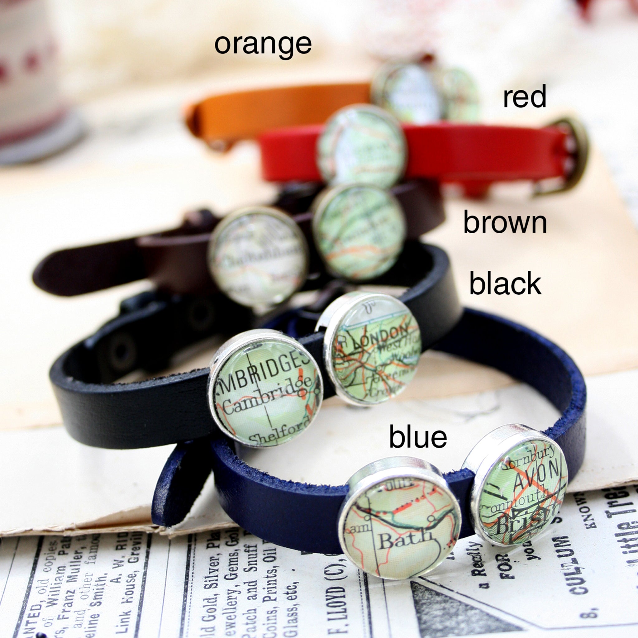 Blue, black, brown, red and orange leather bracelets featuring map locations