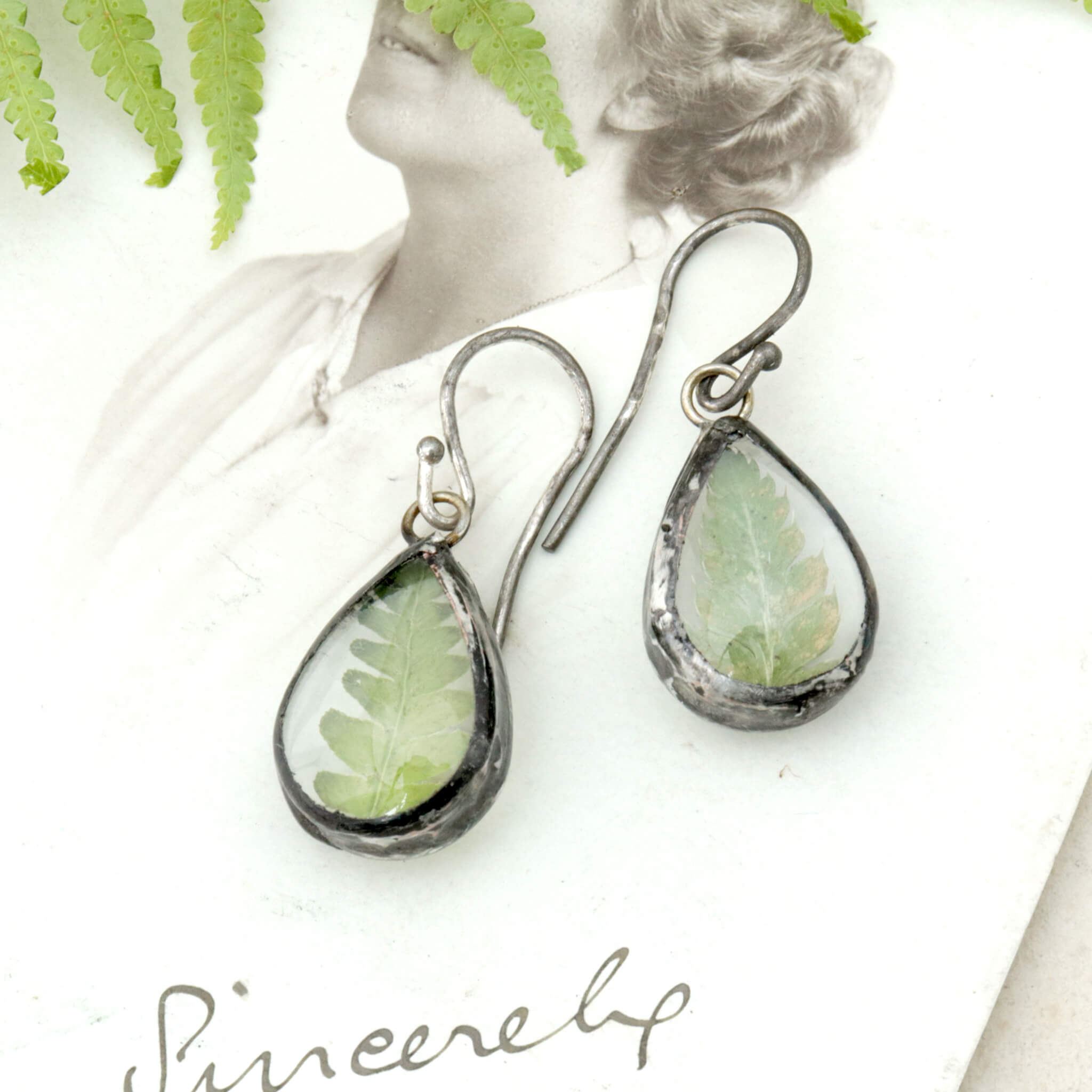 Earrings with real fern lying on an old photo