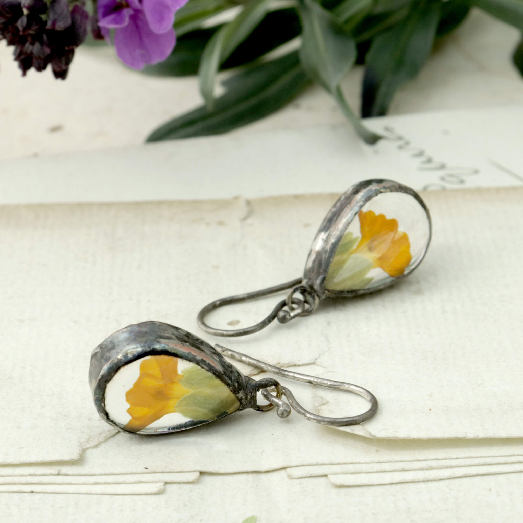 Earrings with real yellow primrose flowers lying on an old letter