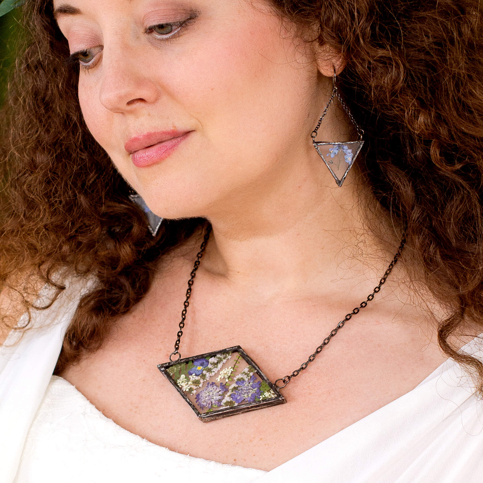 Brunette wearing rhomboidal Purple pressed flower necklace