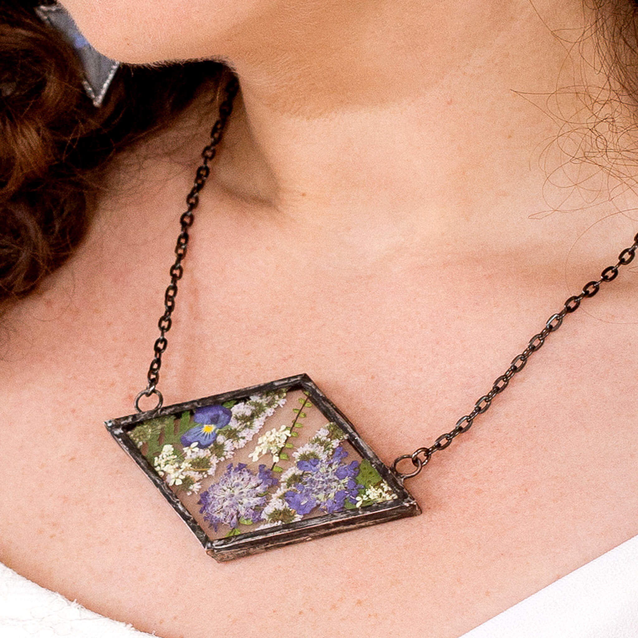 Rhomboidal Purple pressed flower necklace worn on a neck