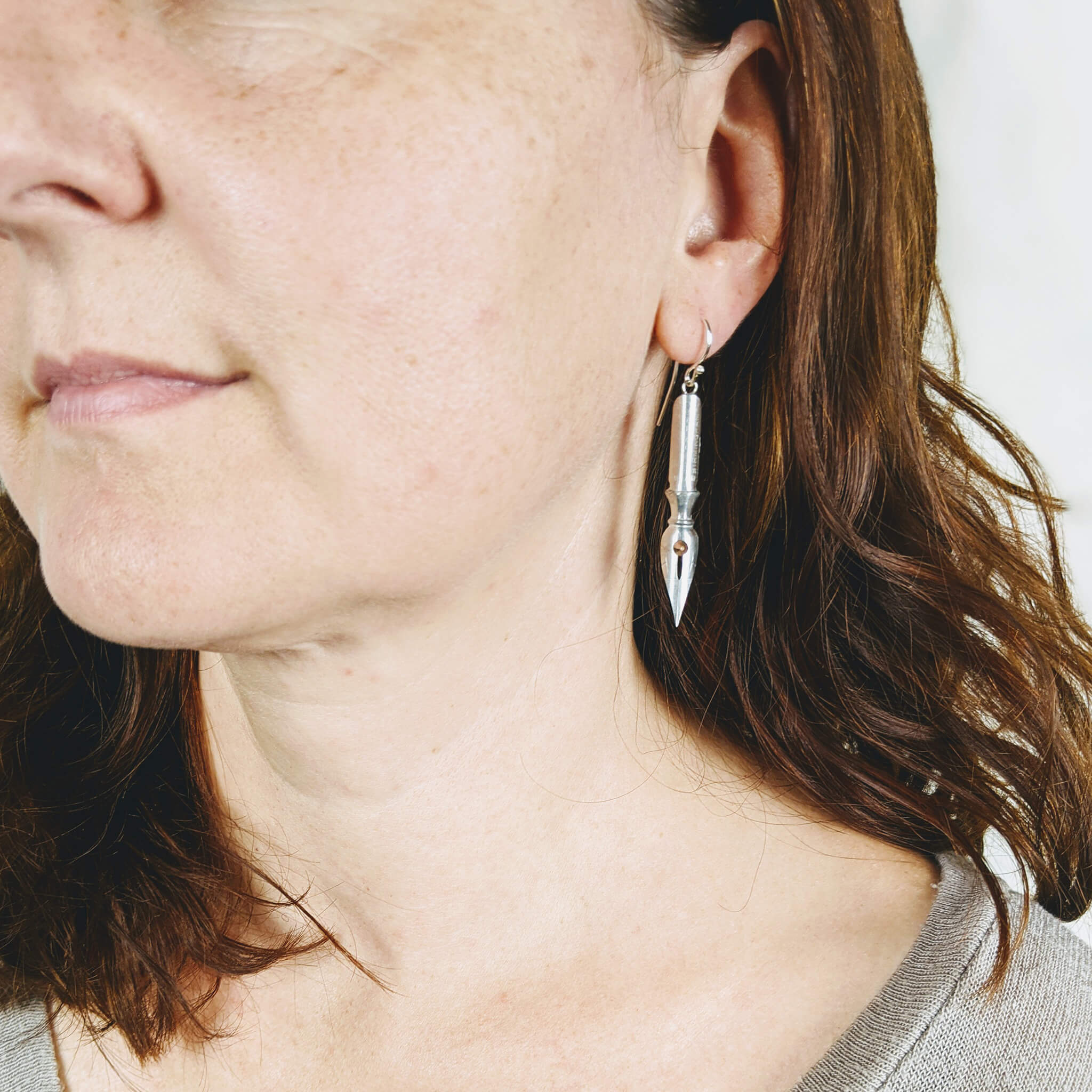 woman wearing pen nib earrings with rose gold crystals on them