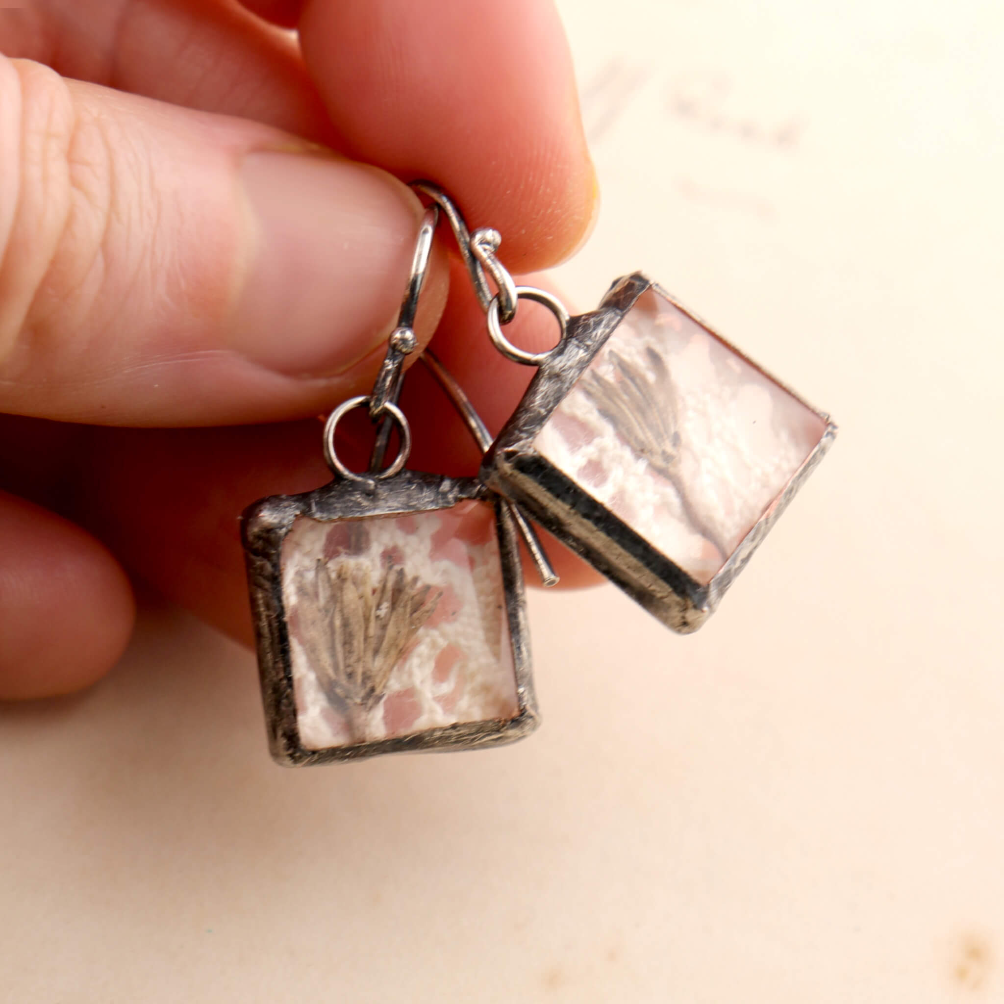 Square soldered earrings with vintage lase and pressed flowers hold in hand