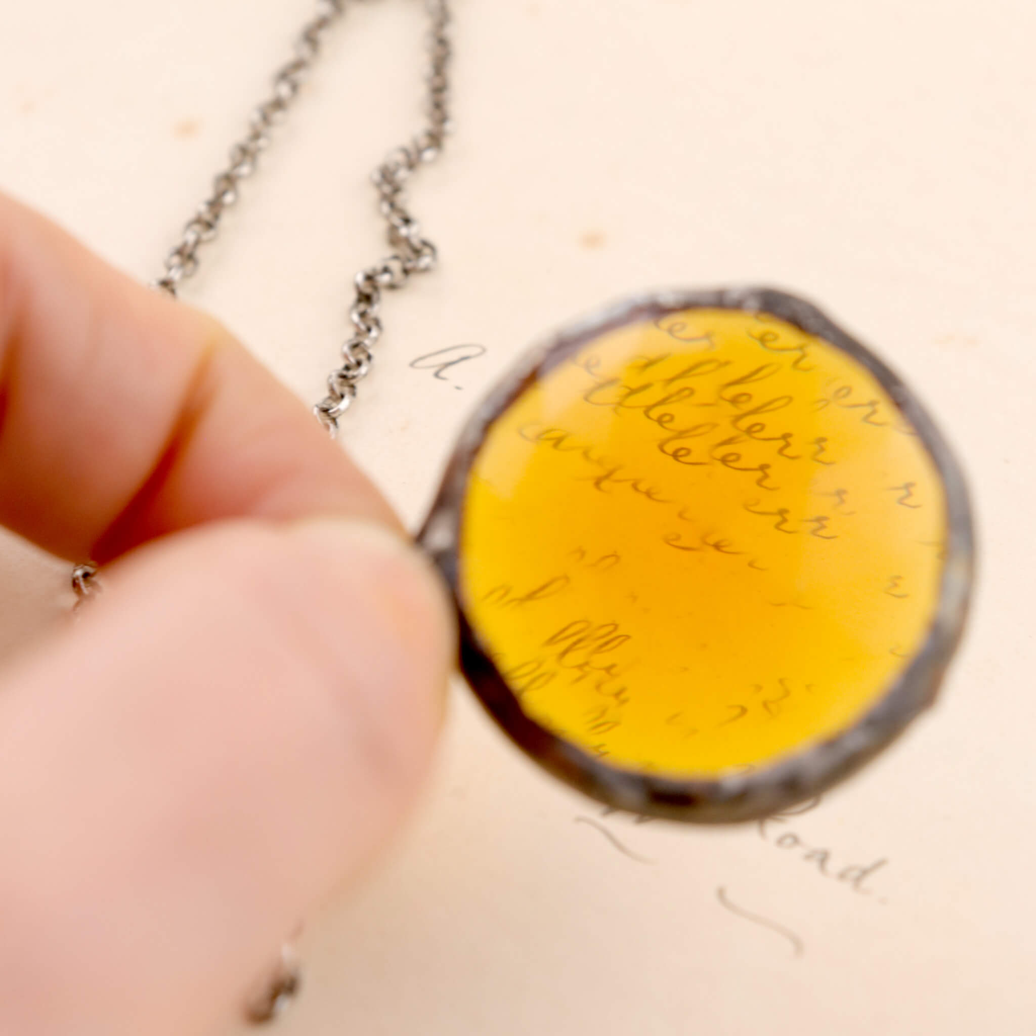 Faceted amber glass framed into necklace hold in hand