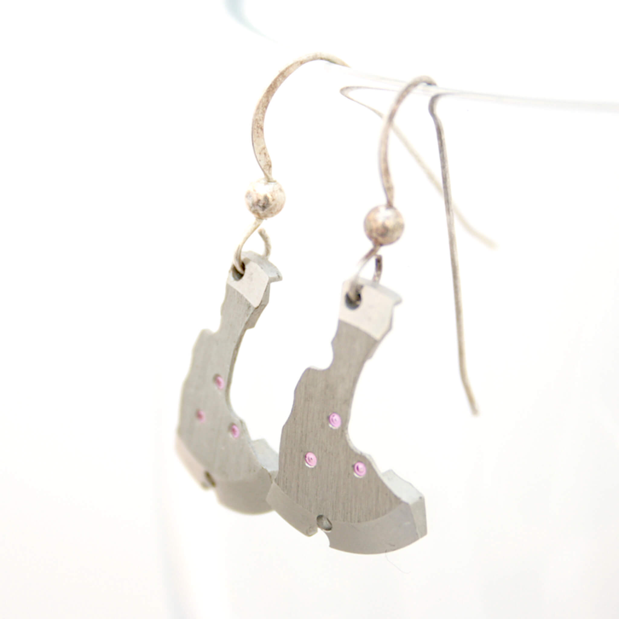 watch parts turned into dangling earrings hanging on a glass