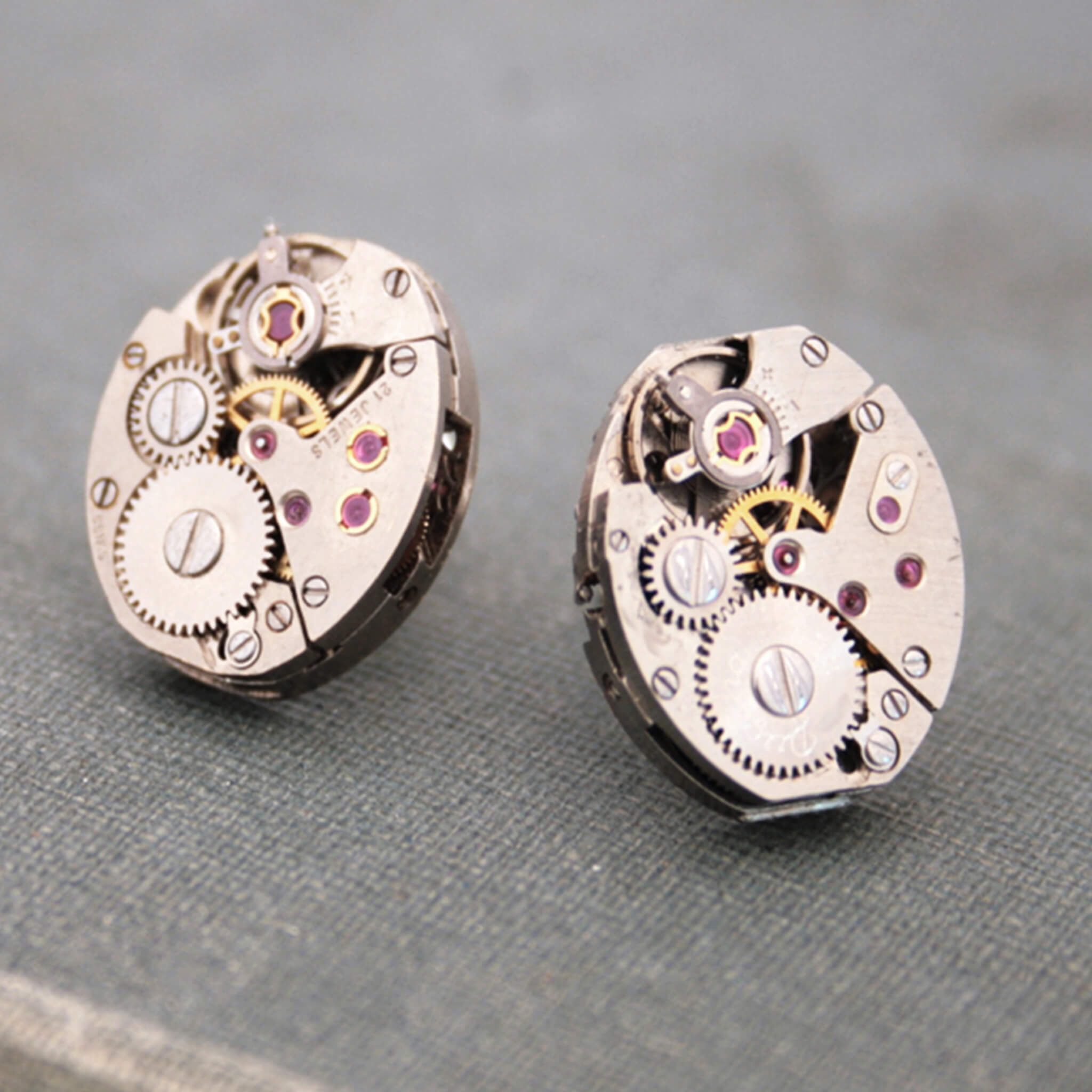 Oval watch movements turned into stud earrings lying on a vintage book