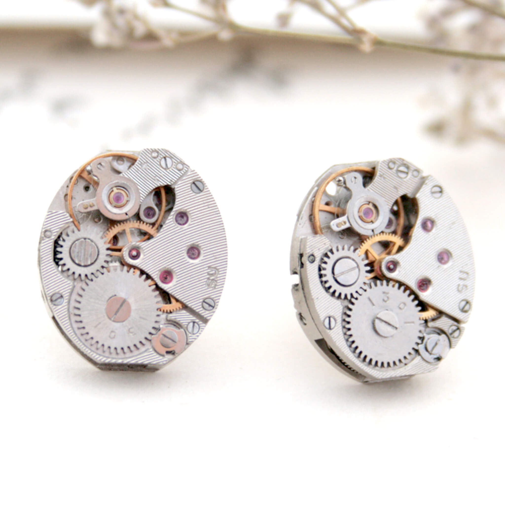 Watch movements turned into stud earrings lying on a vintage paper