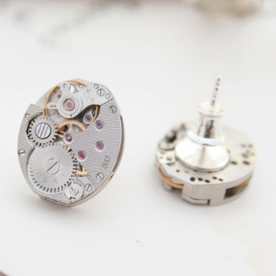 Watch movements turned into stud earrings lying on a vintage paper