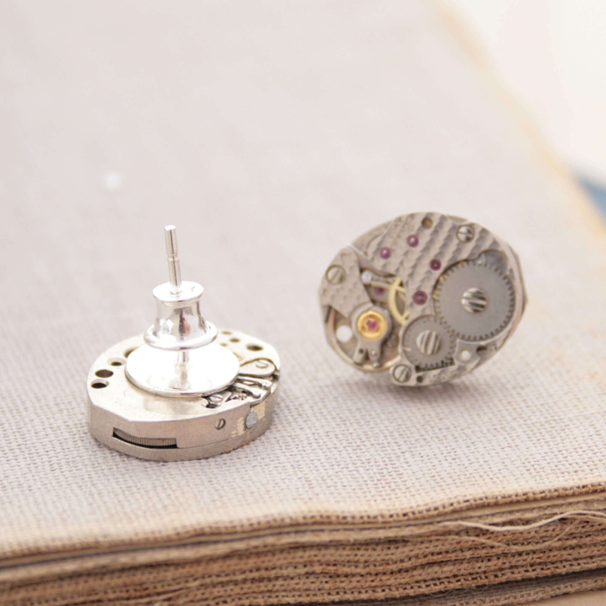 watch movements turned into stud earrings lying on an old book