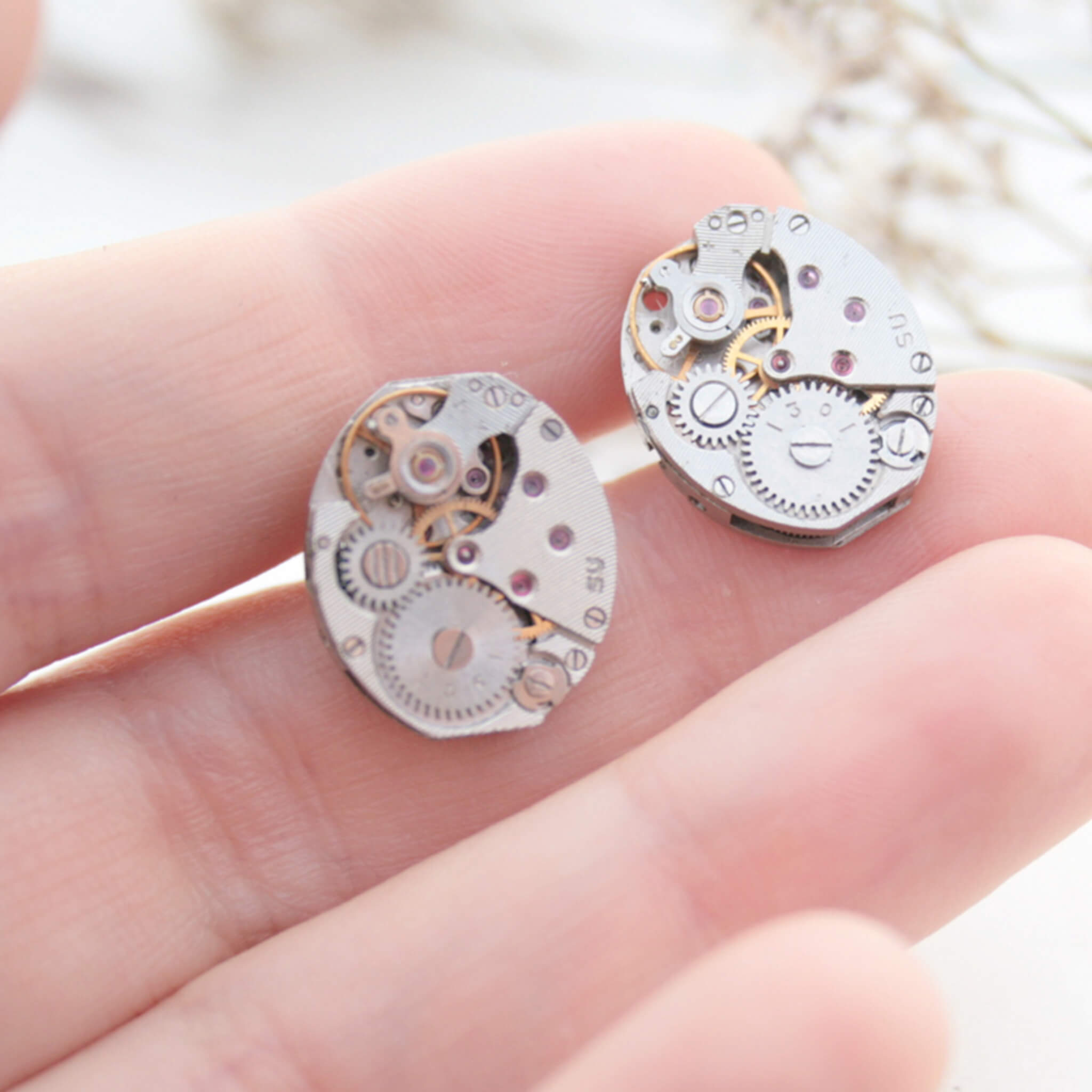 watch movements turned into stud earrings being hold in hand