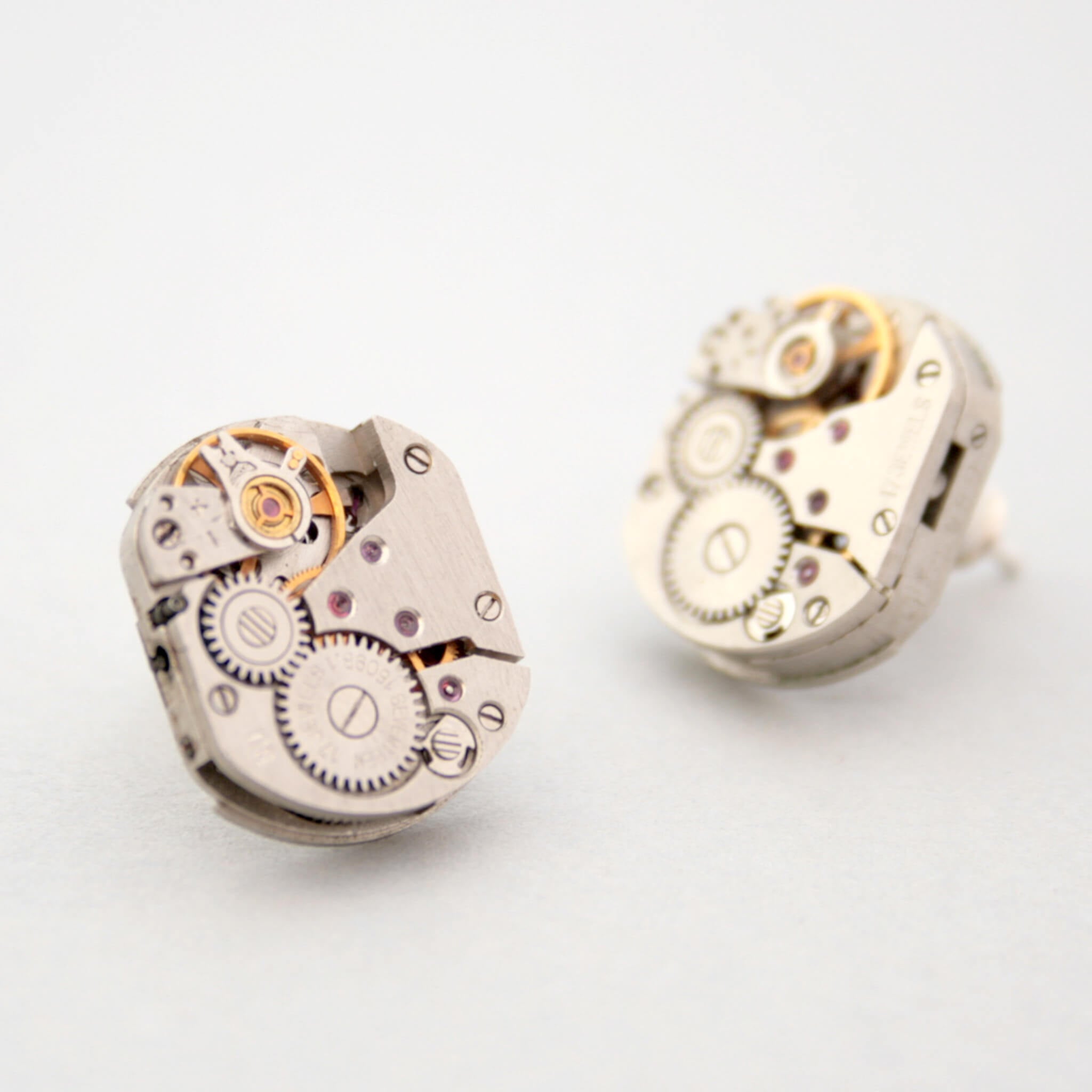 watch movements turned into stud earrings lying on a white paper
