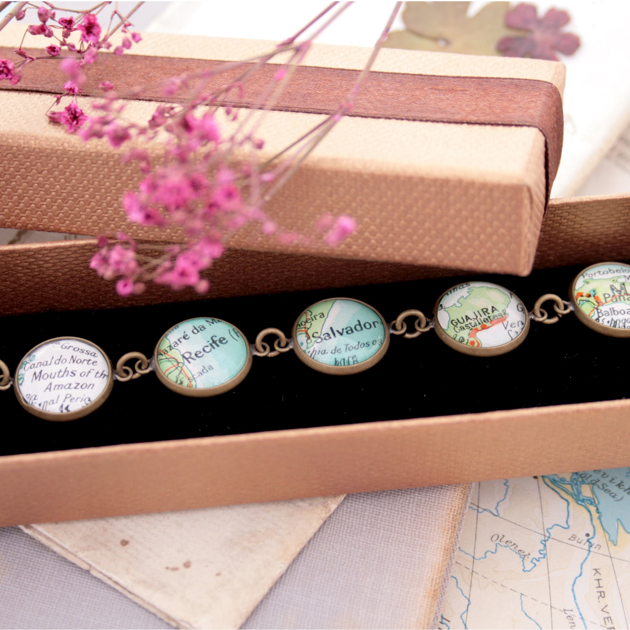 Antique bronze beaded bracelet featuring different map locations in a brown box