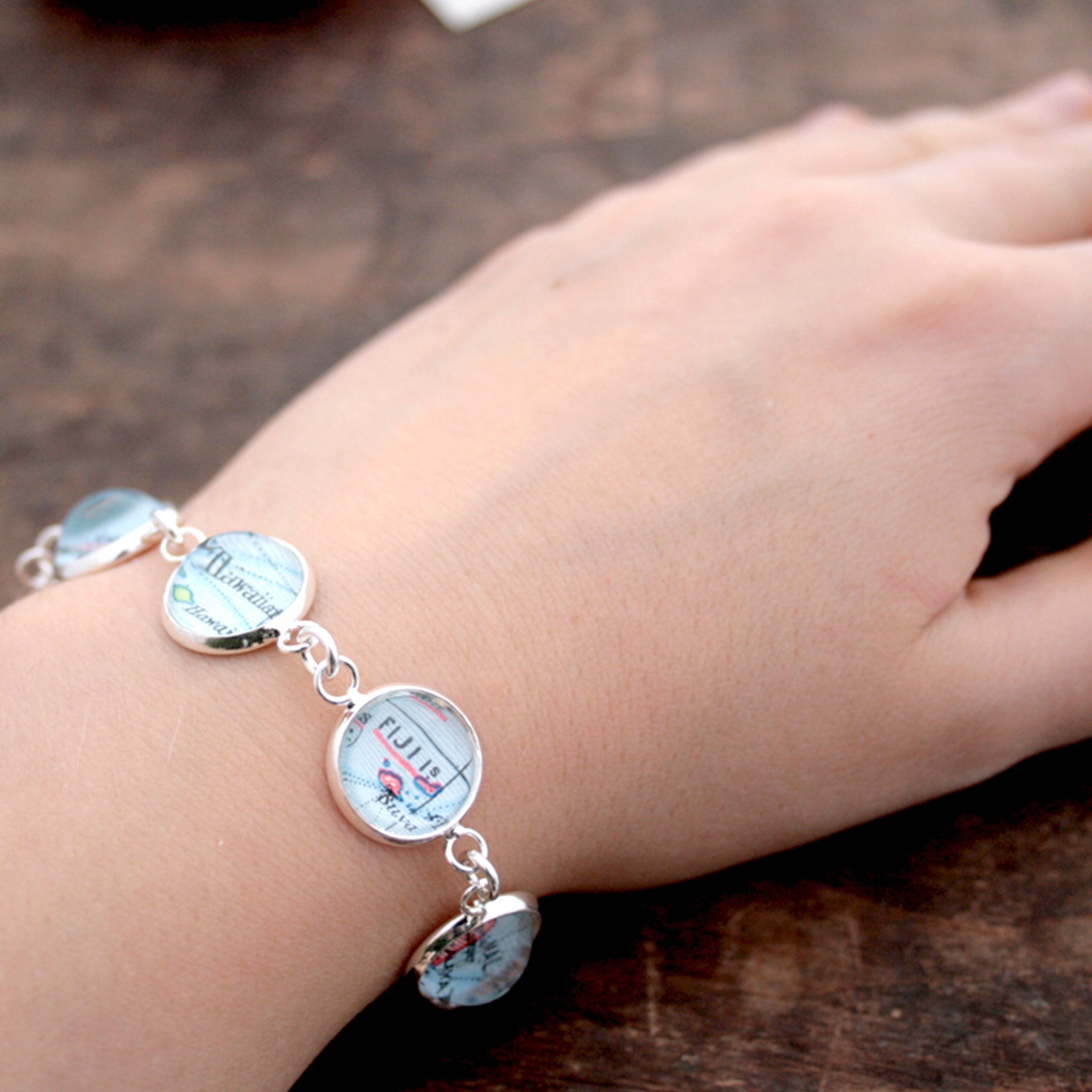 Worn on hand silver tone beaded bracelet featuring different map locations