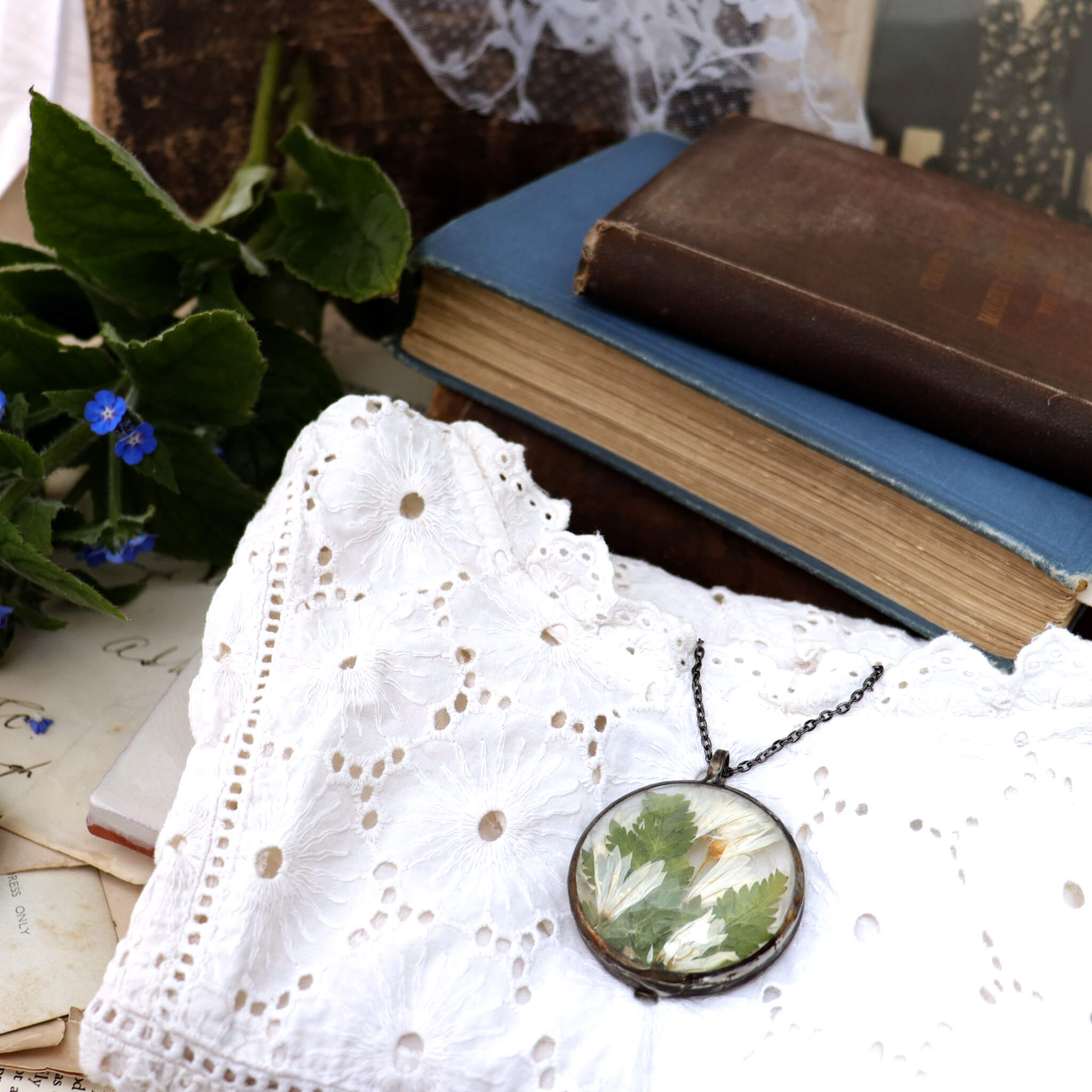 White blouse in right bottom corner, large necklace lying on top, vintage books & frame in the back